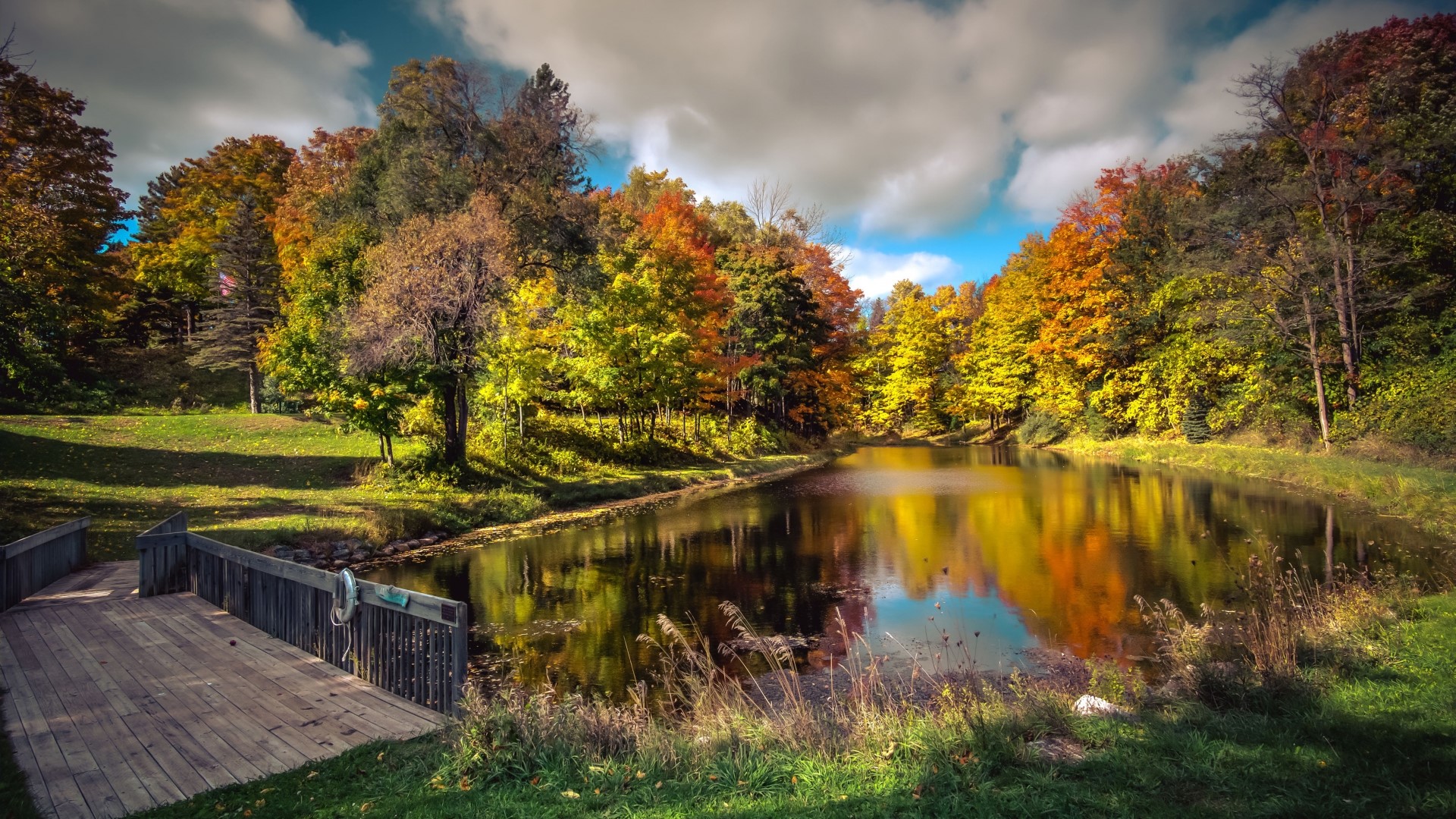 Autumn trees reflecting in a lake with a wooden dock HD Wallpaper