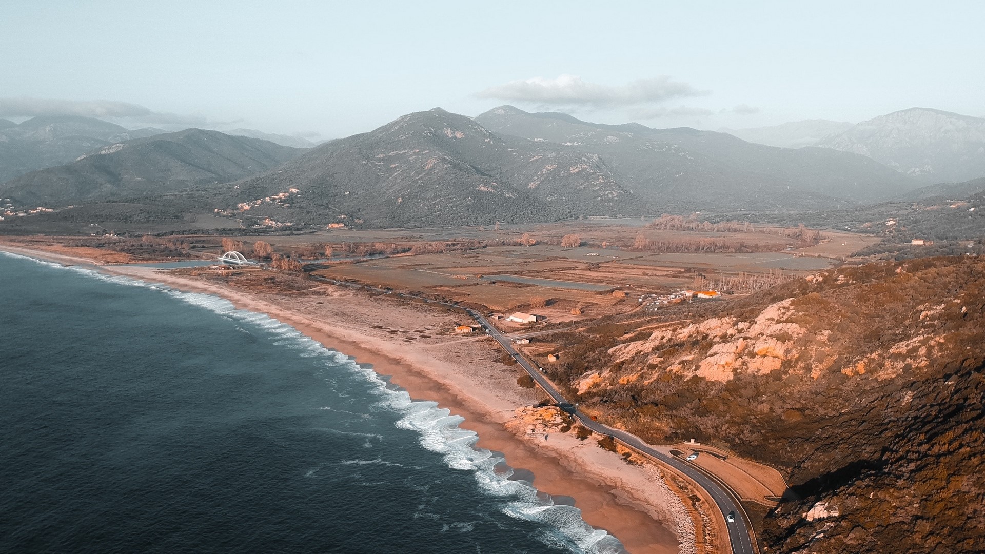 Aerial view of a coastal road and mountains HD Wallpaper