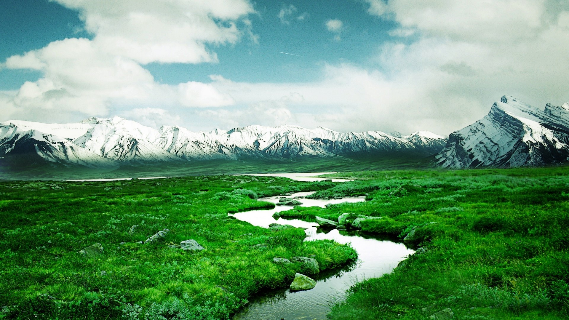 Snow-capped mountains and a winding river in a green valley HD Wallpaper