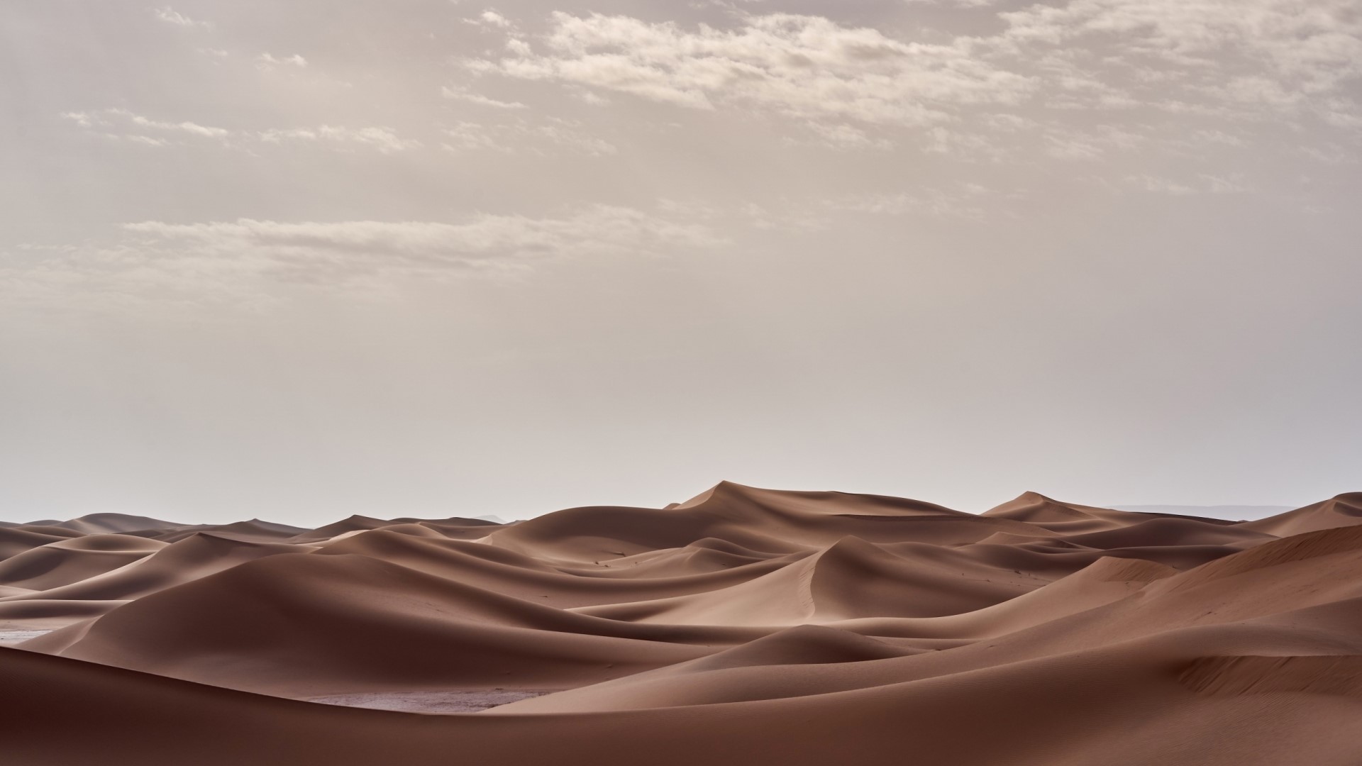Desert dunes under a cloudy sky HD Wallpaper