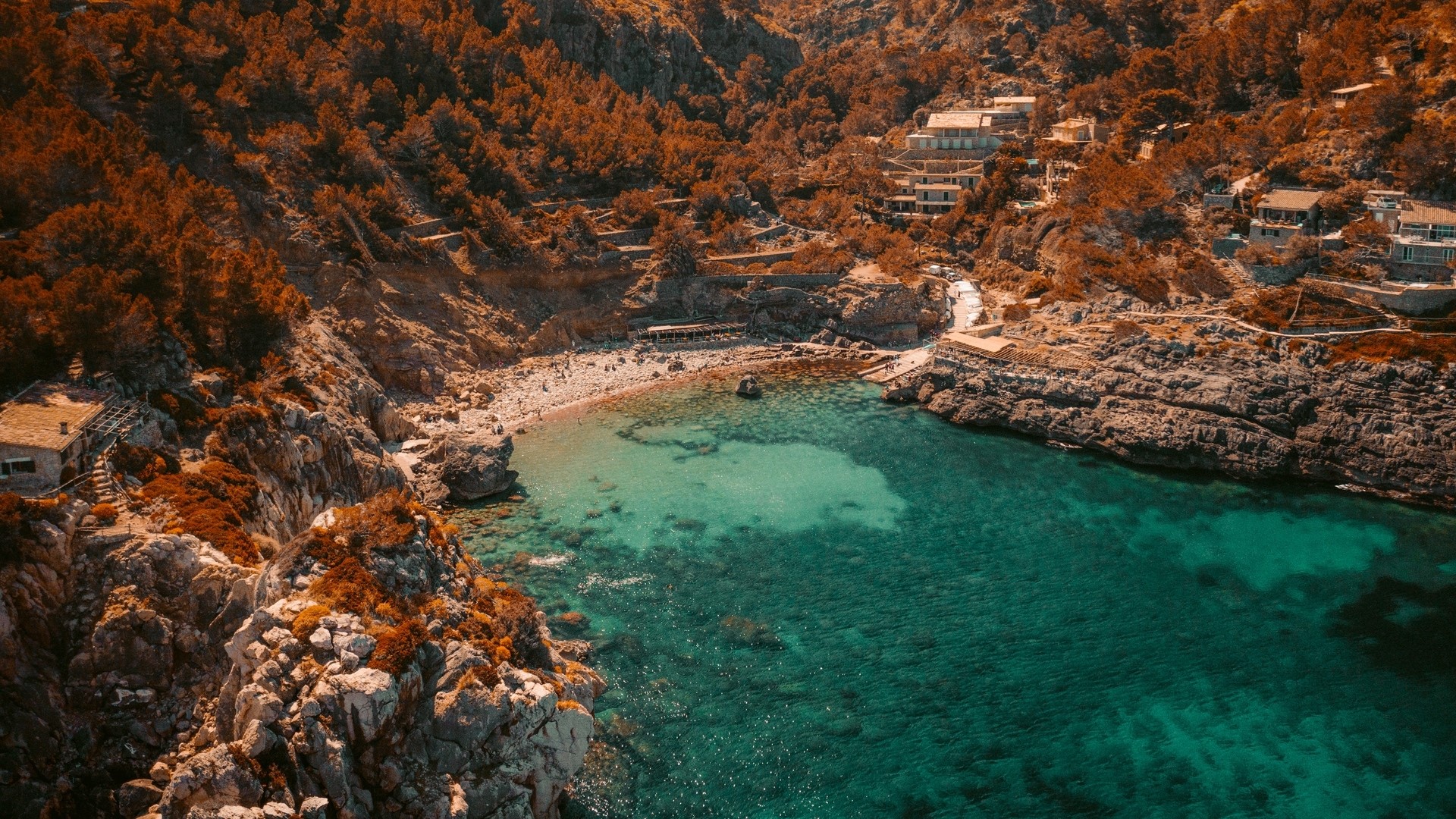 Aerial view of a secluded cove with turquoise water and rocky cliffs HD Wallpaper