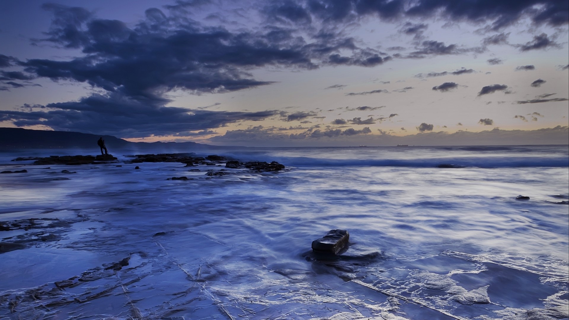 Man standing on rocks at coast during sunset HD Wallpaper
