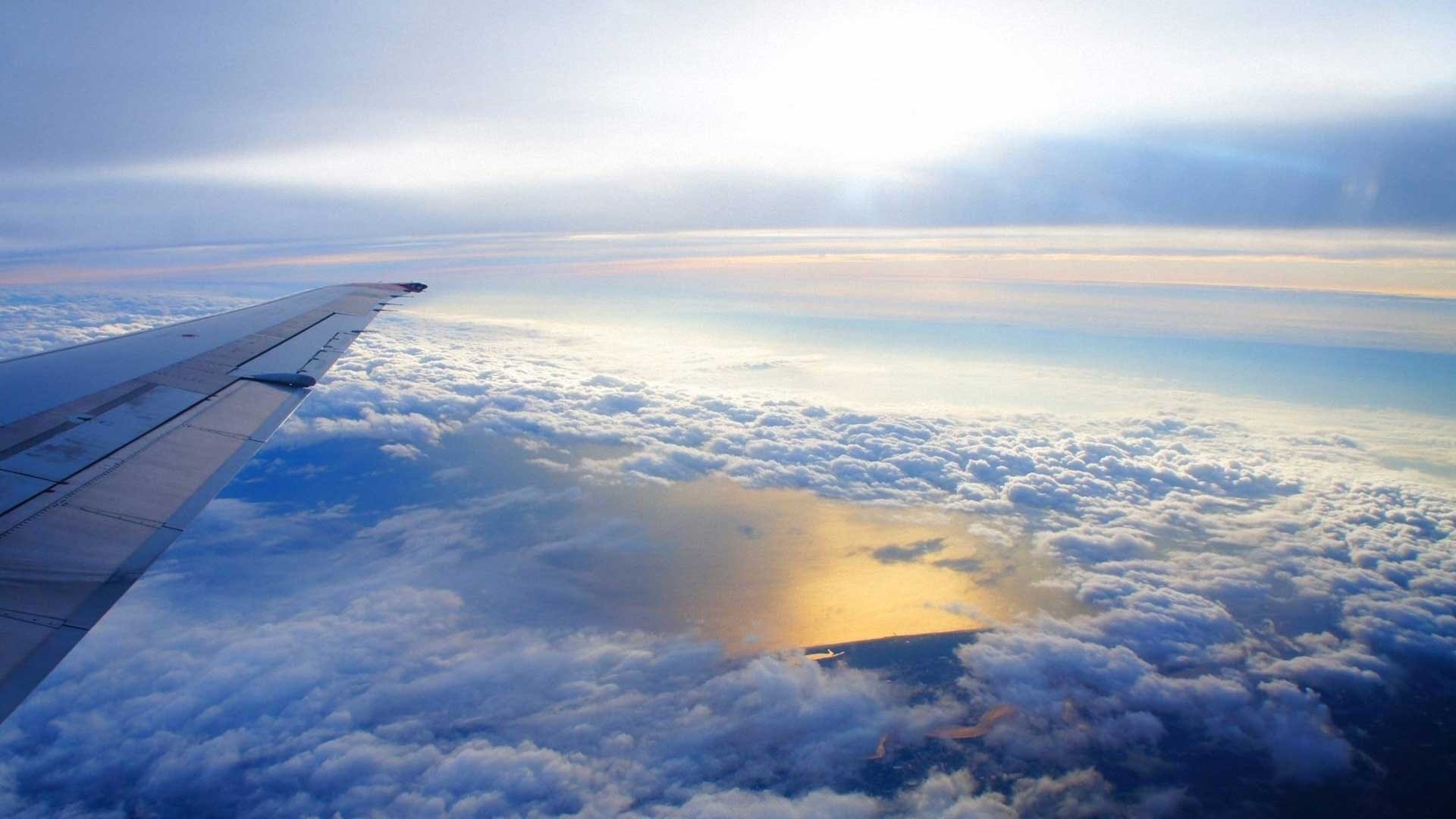 Airplane wing over clouds and ocean HD Wallpaper