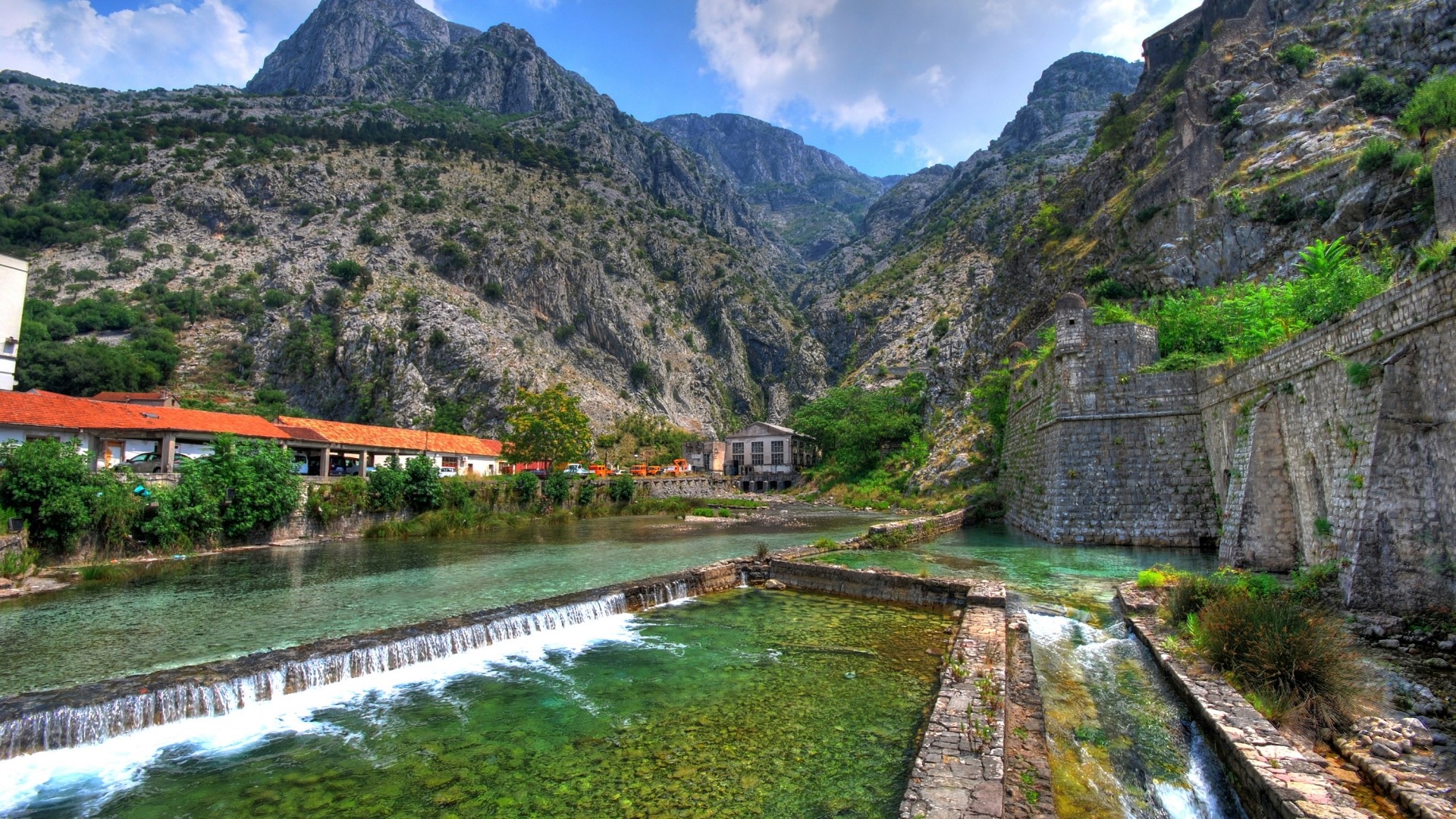 River flowing through a valley with mountains and old stone walls HD Wallpaper
