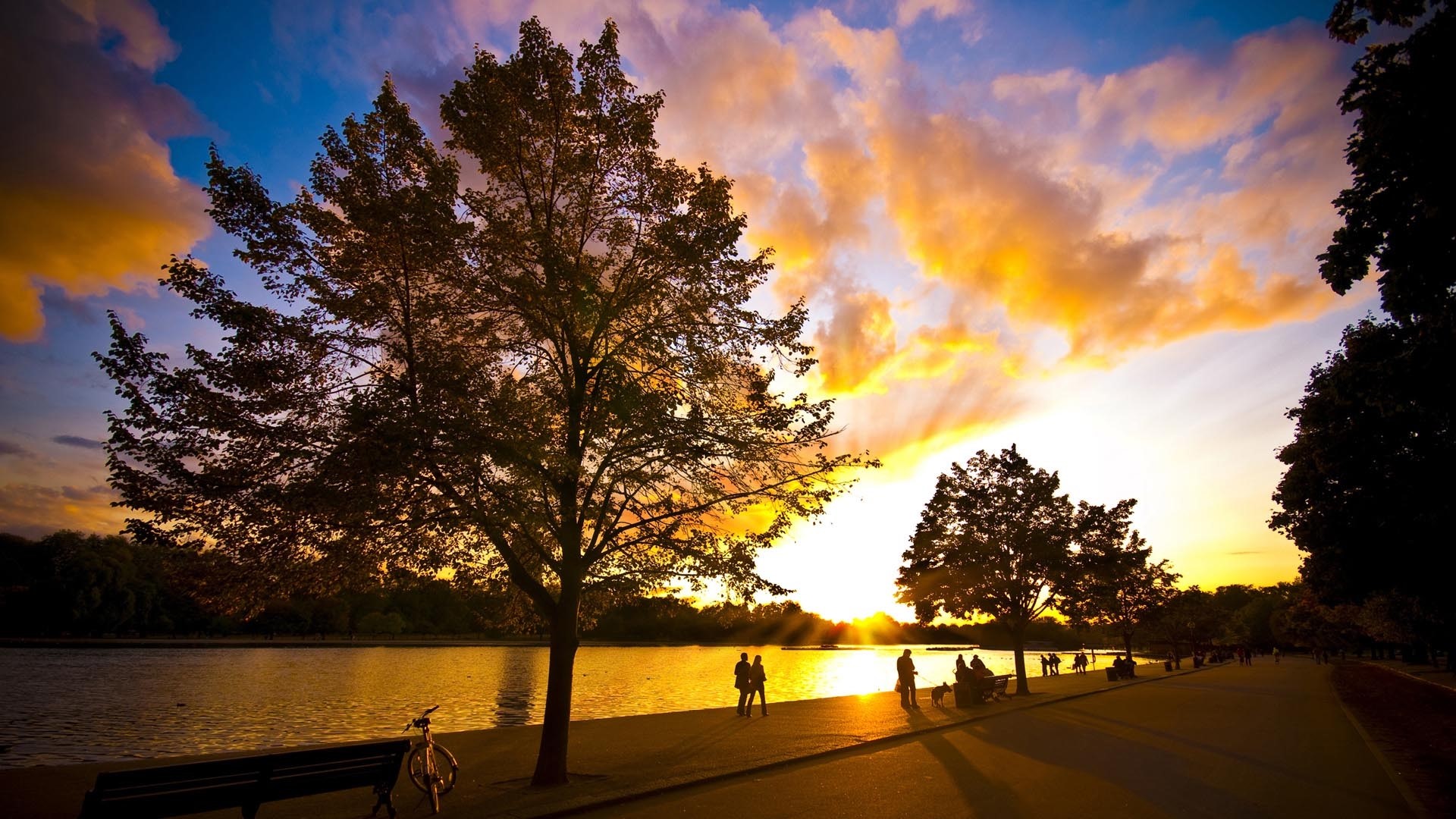 Sunset over a lake with people walking HD Wallpaper