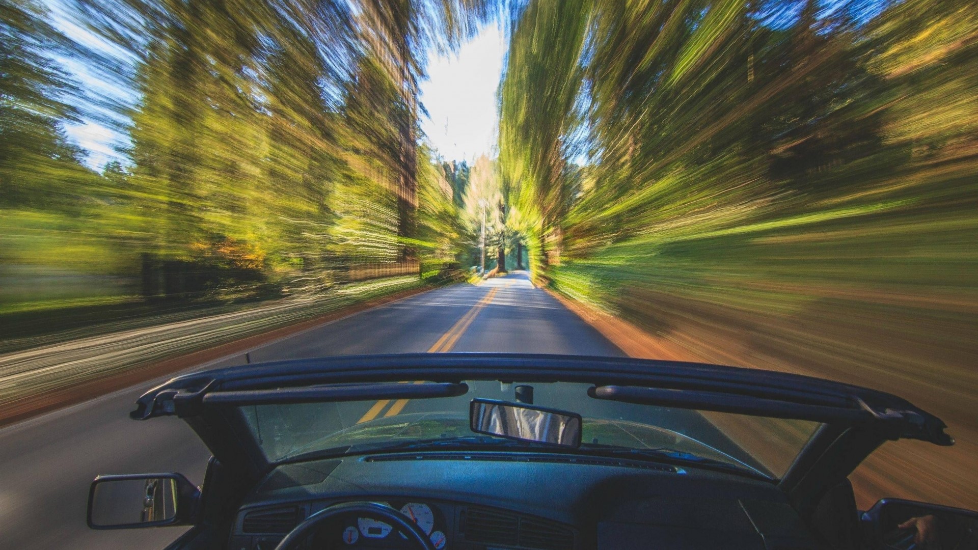 Convertible car driving on a tree-lined road HD Wallpaper