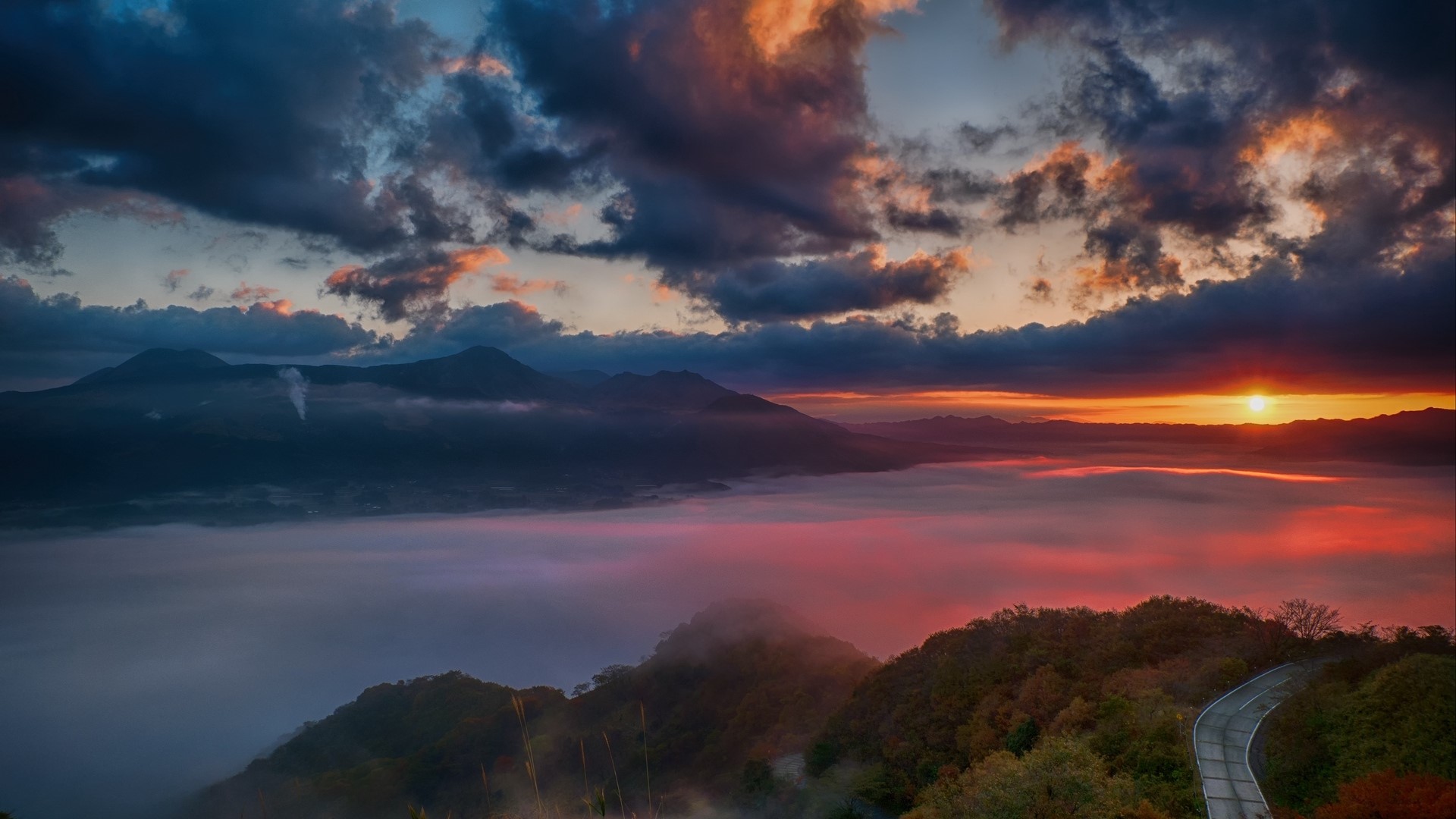 Sunrise over misty mountains with a winding road HD Wallpaper