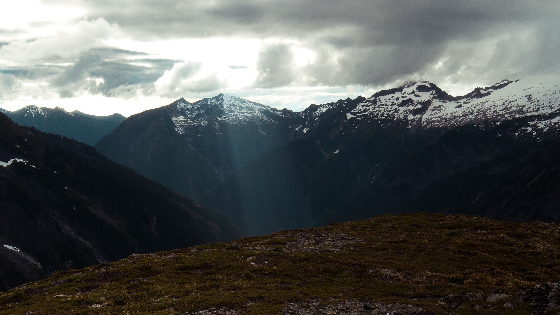 Mountain peaks with snow under cloudy sky HD Wallpaper