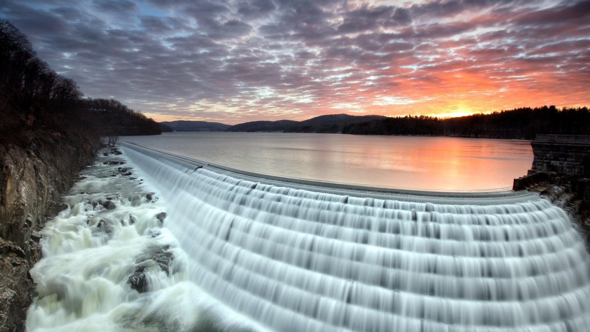 Waterfall cascading over a dam at sunset HD Wallpaper