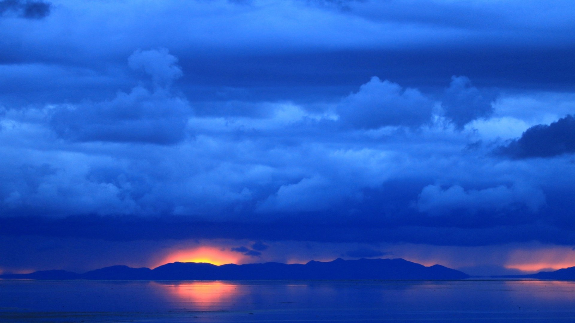 Blue clouds over a body of water at dawn HD Wallpaper