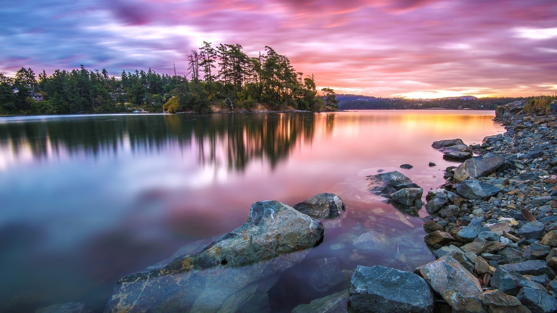 Sunset over a calm lake with rocky shore HD Wallpaper