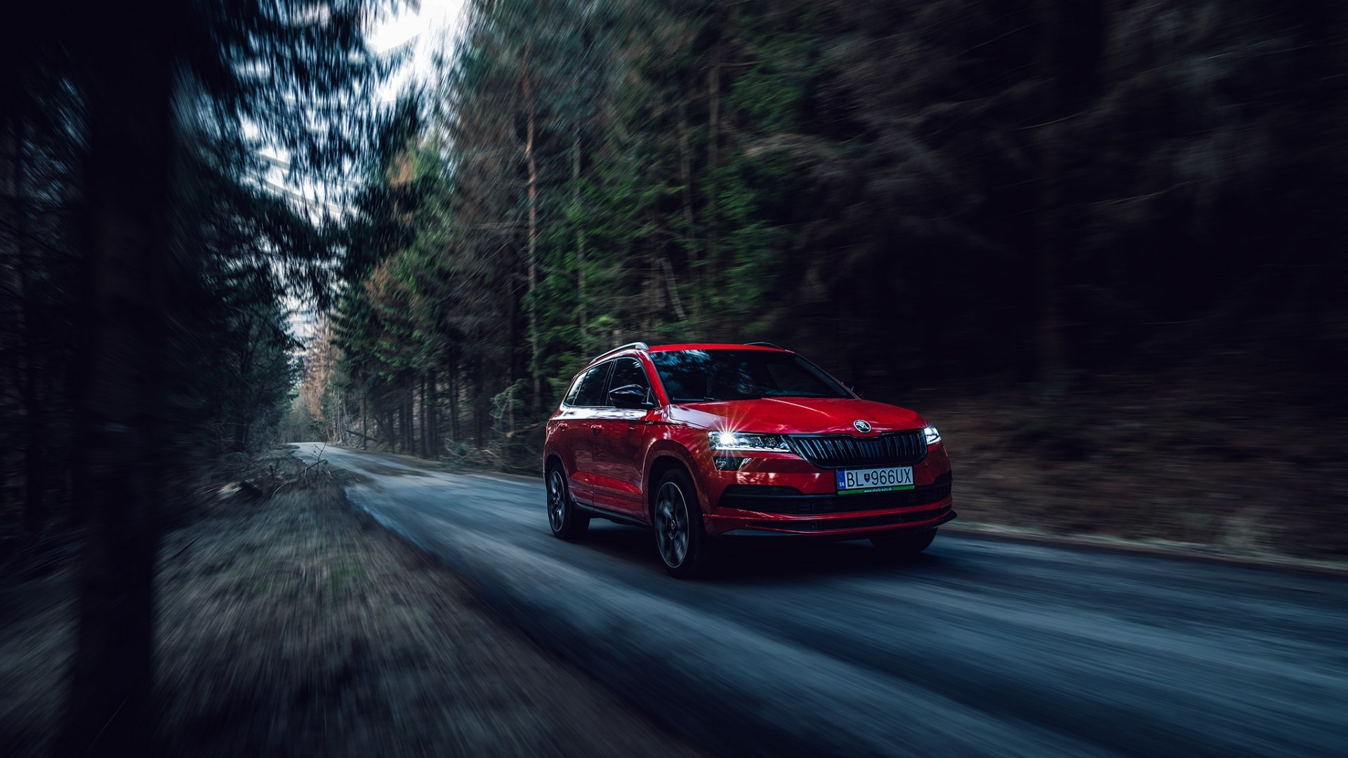 Red Skoda Karoq SportLine driving on a forest road HD Wallpaper