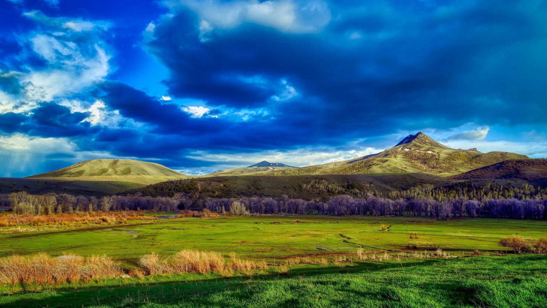 Dramatic sky over rolling green hills and mountains HD Wallpaper