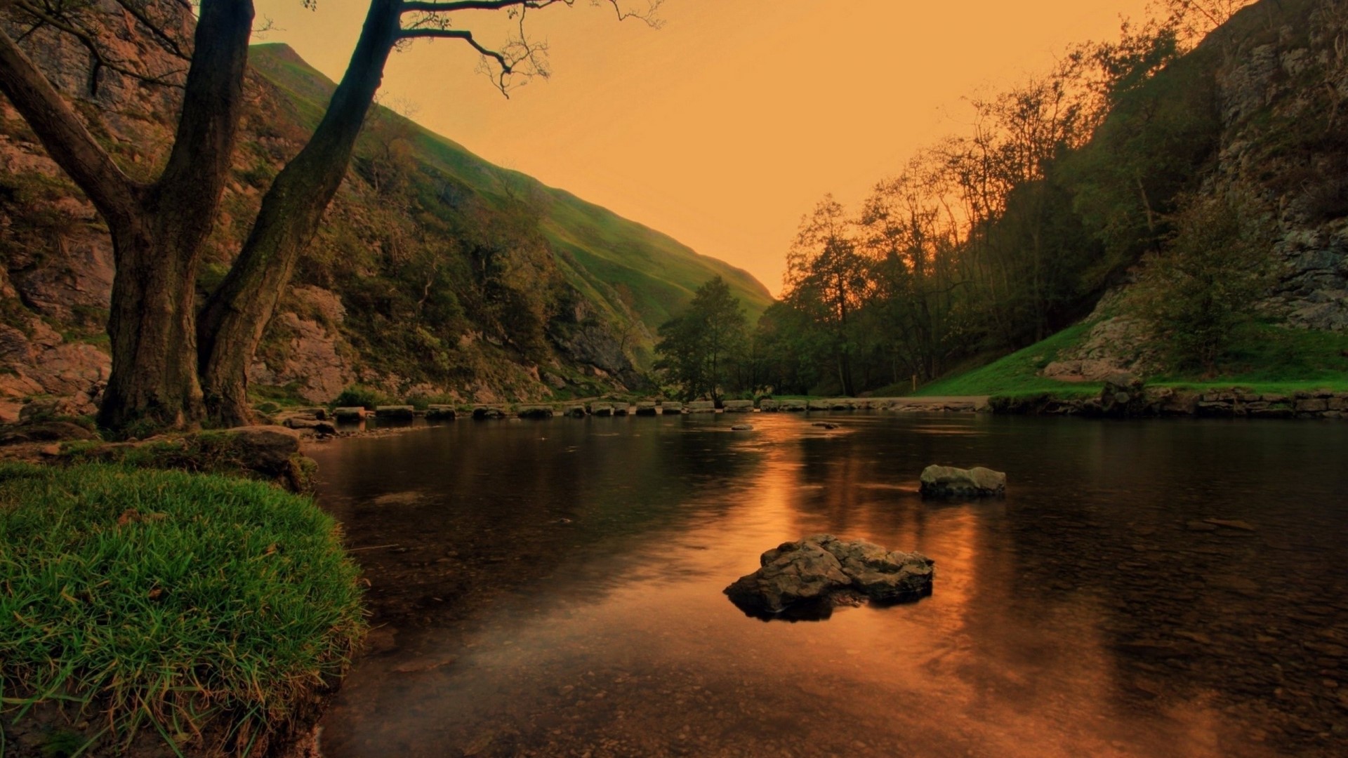 Stepping stones across a river at sunset HD Wallpaper