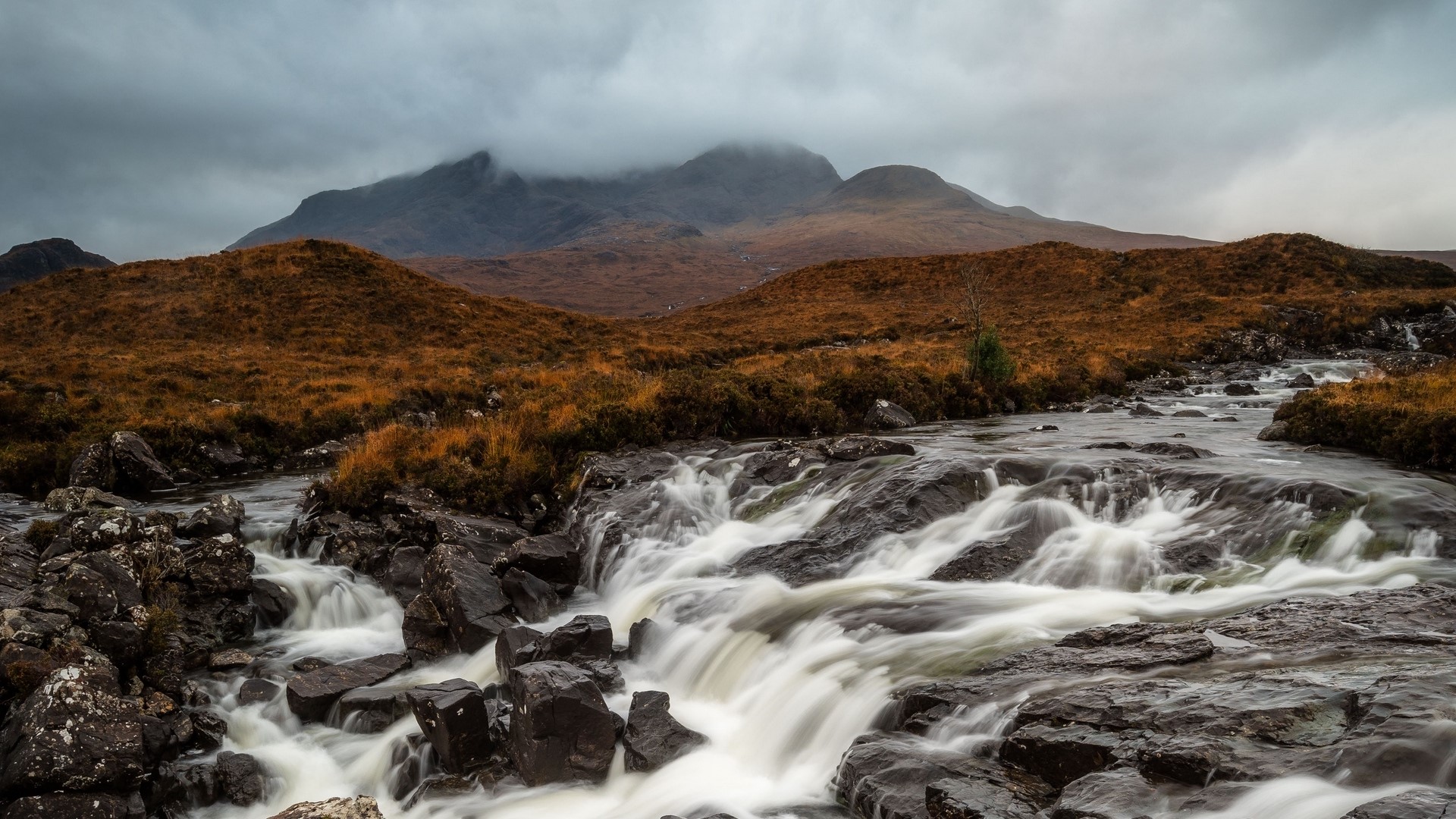 River flowing over rocks with mountains in background HD Wallpaper