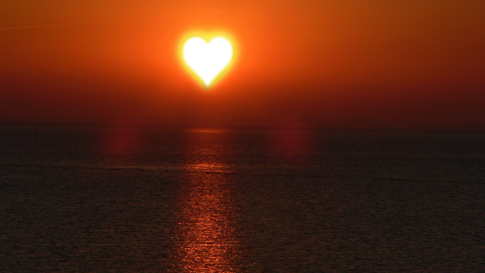 Heart-shaped sun setting over the ocean HD Wallpaper