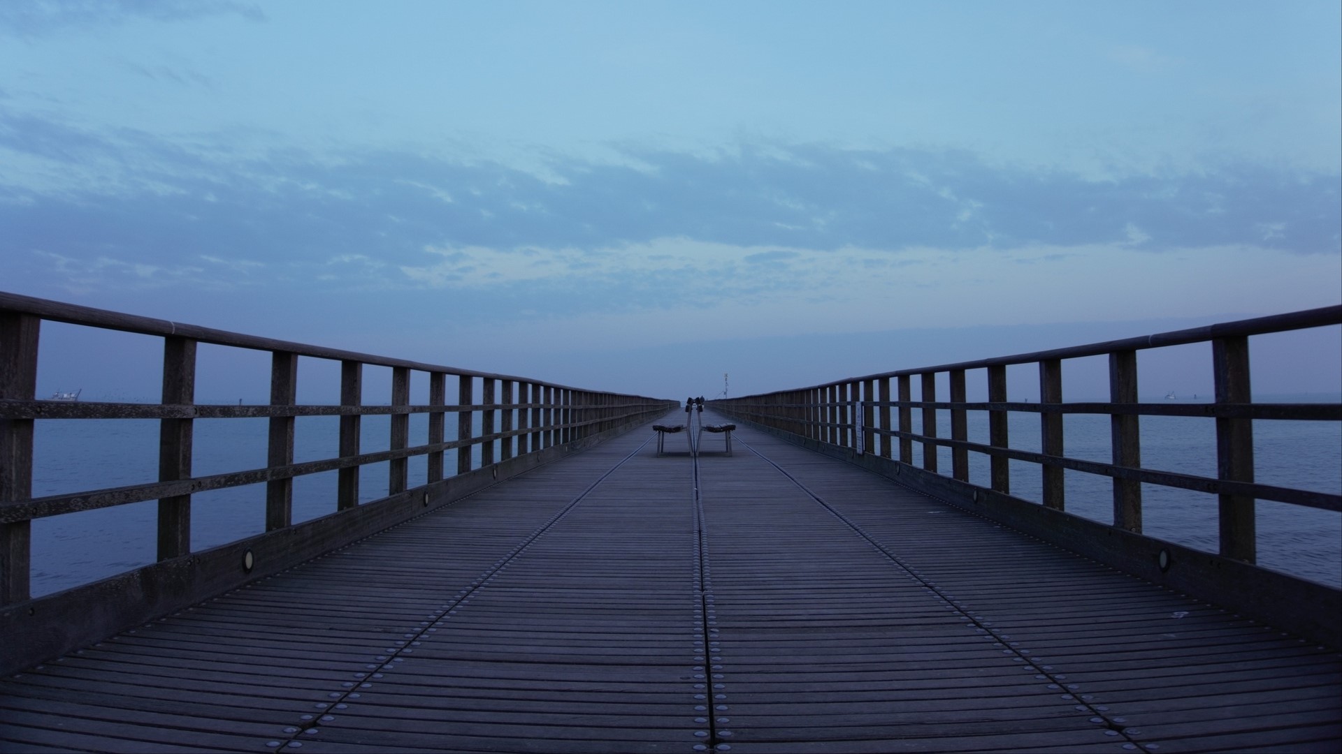 Wooden pier with benches over the ocean at dusk HD Wallpaper