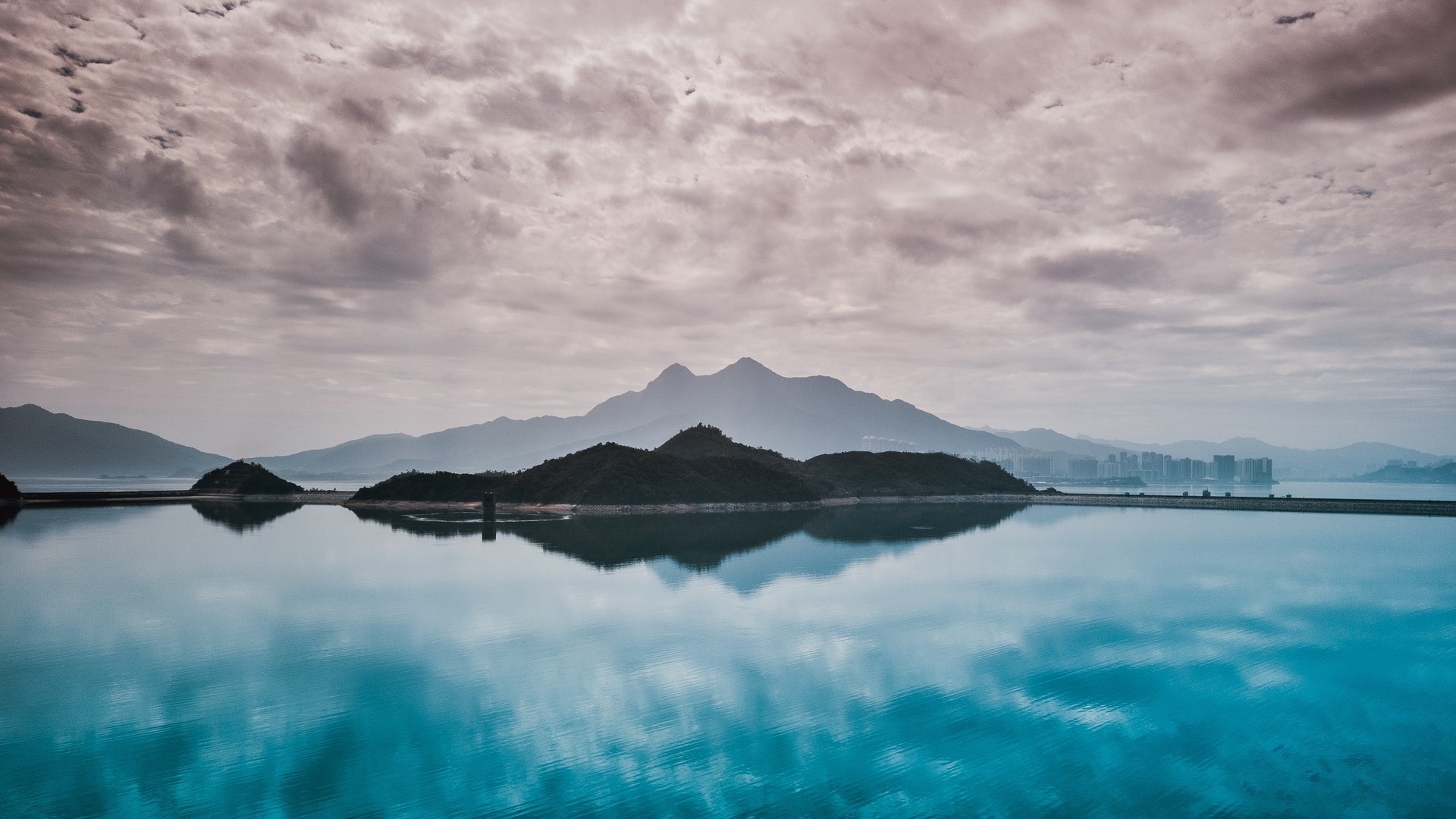 Island and mountains reflected in calm water under cloudy sky HD Wallpaper