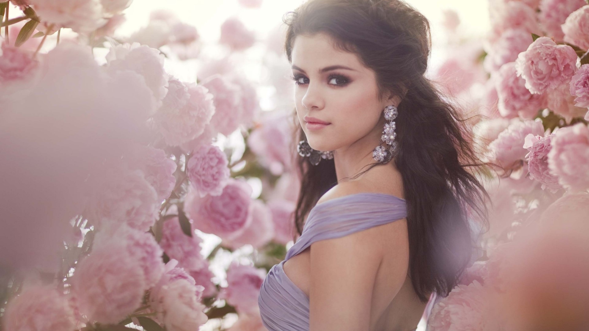 Selena Gomez in a purple dress surrounded by pink flowers HD Wallpaper