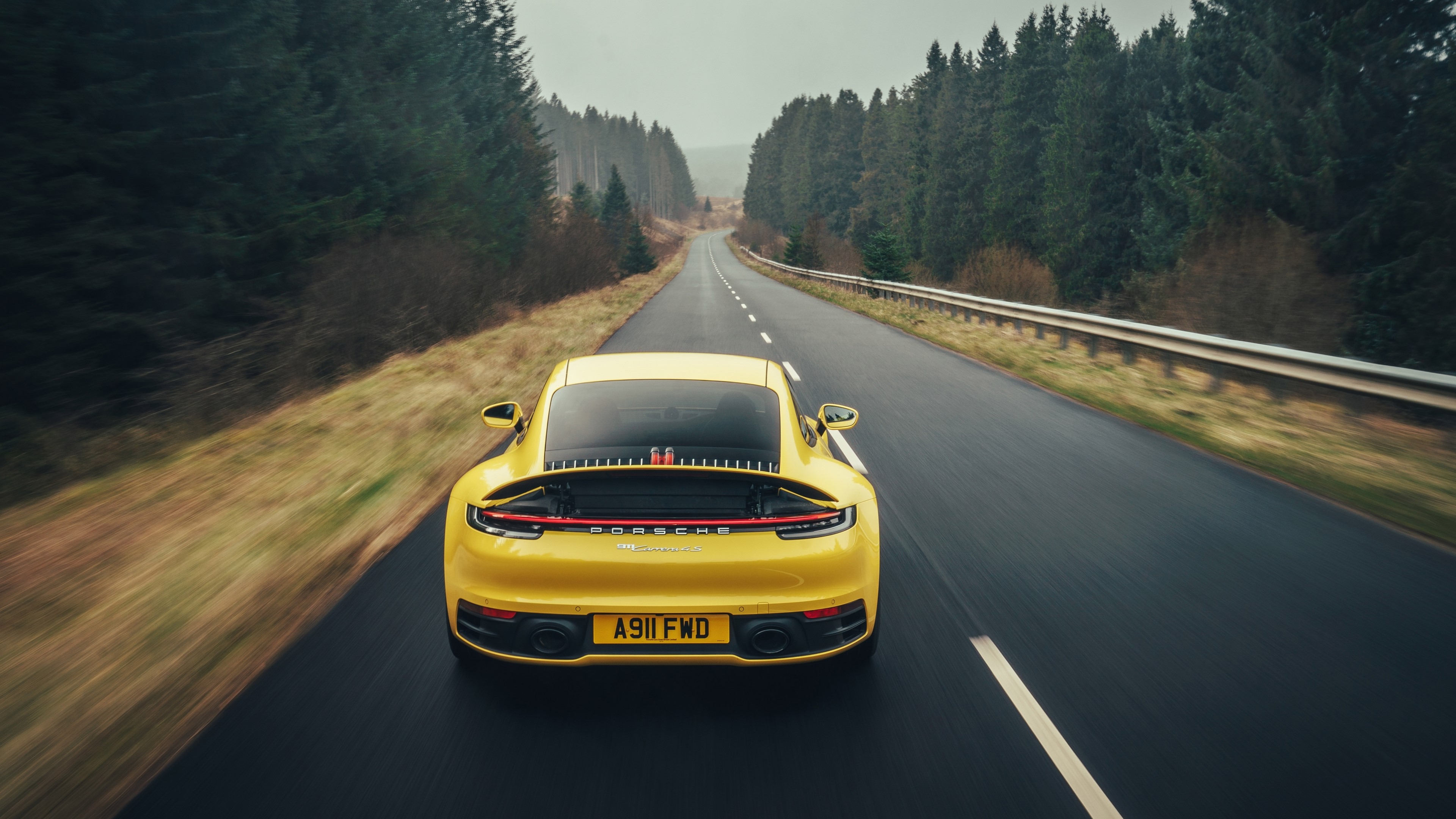 Yellow Porsche 911 driving on a forest road HD Wallpaper