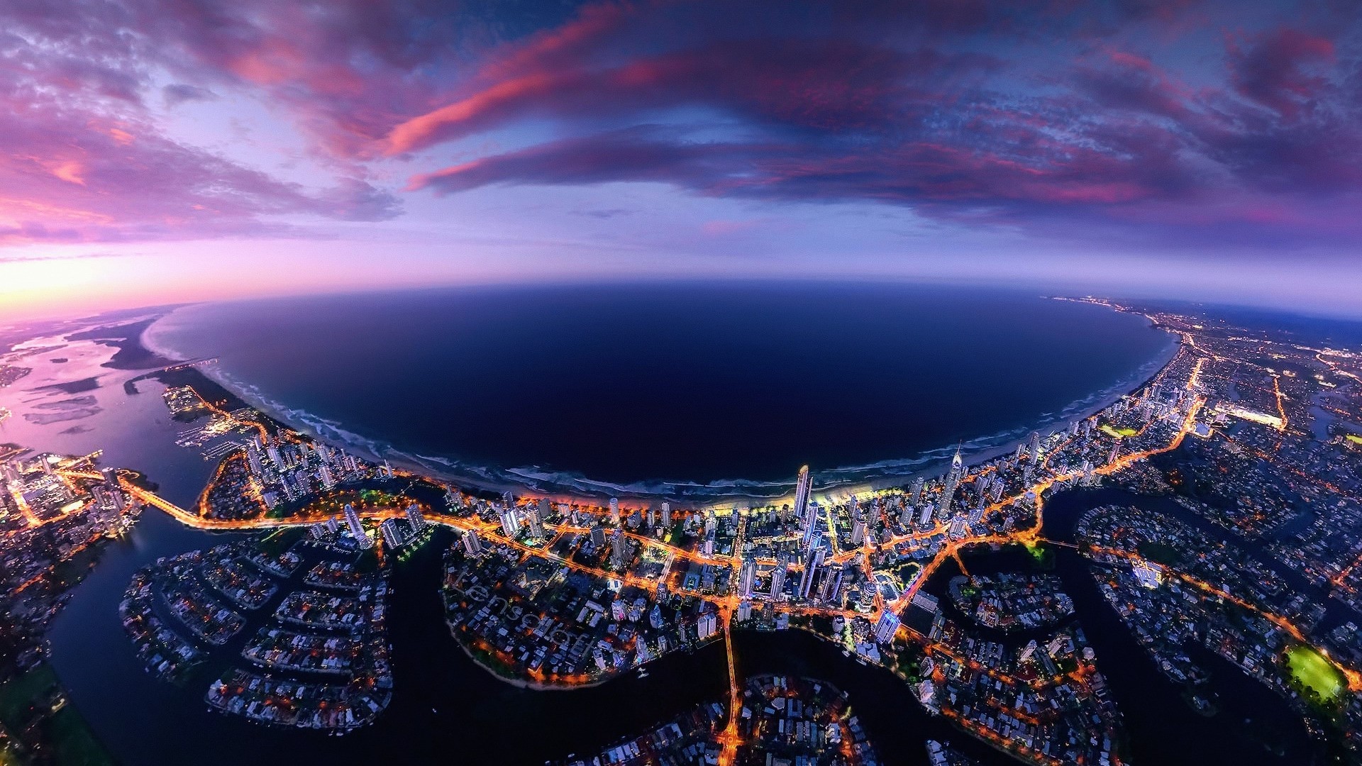 Aerial view of a coastal city at sunset HD Wallpaper