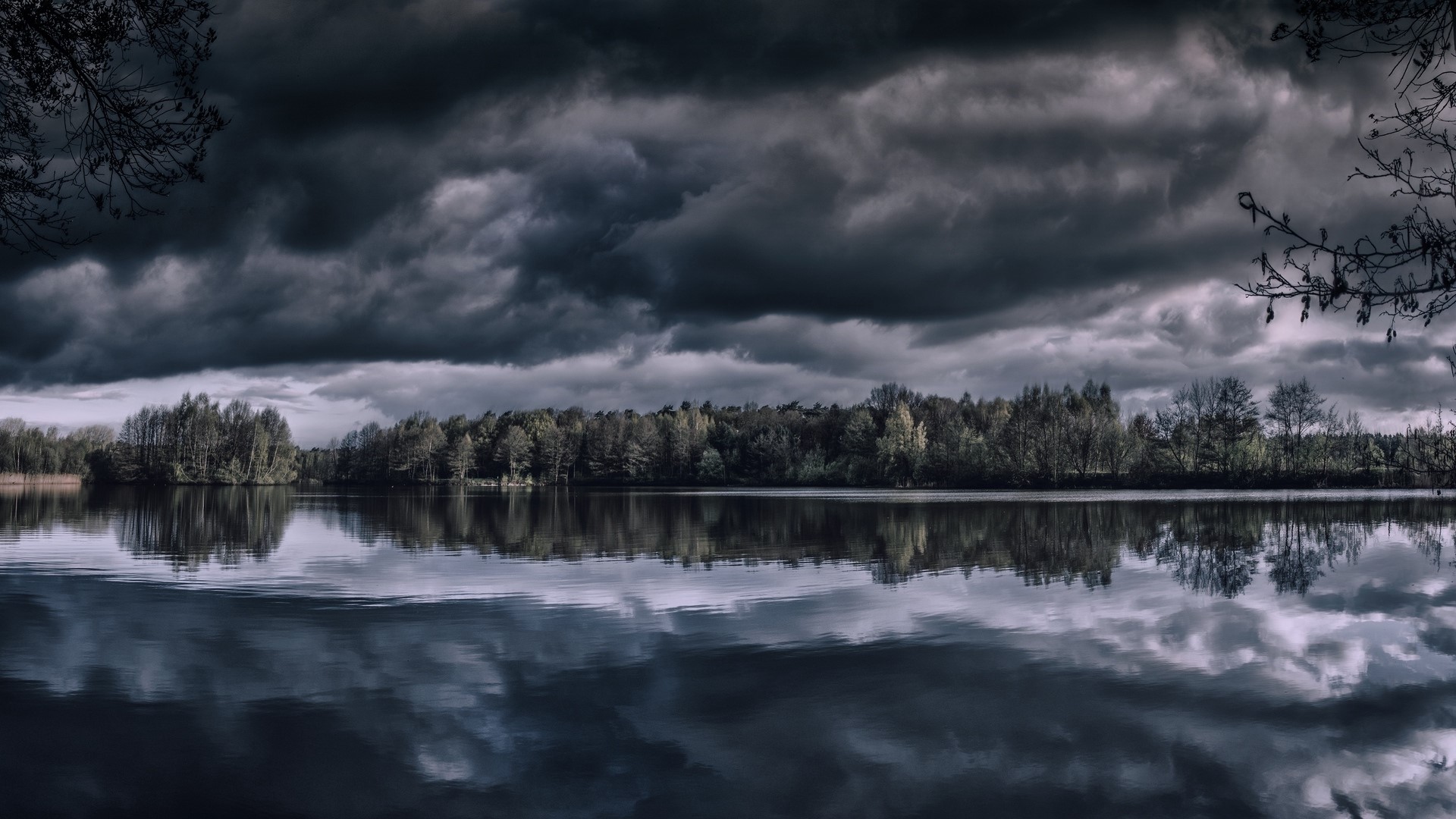 Dark Clouds Over a Reflective Lake and Forest HD Wallpaper