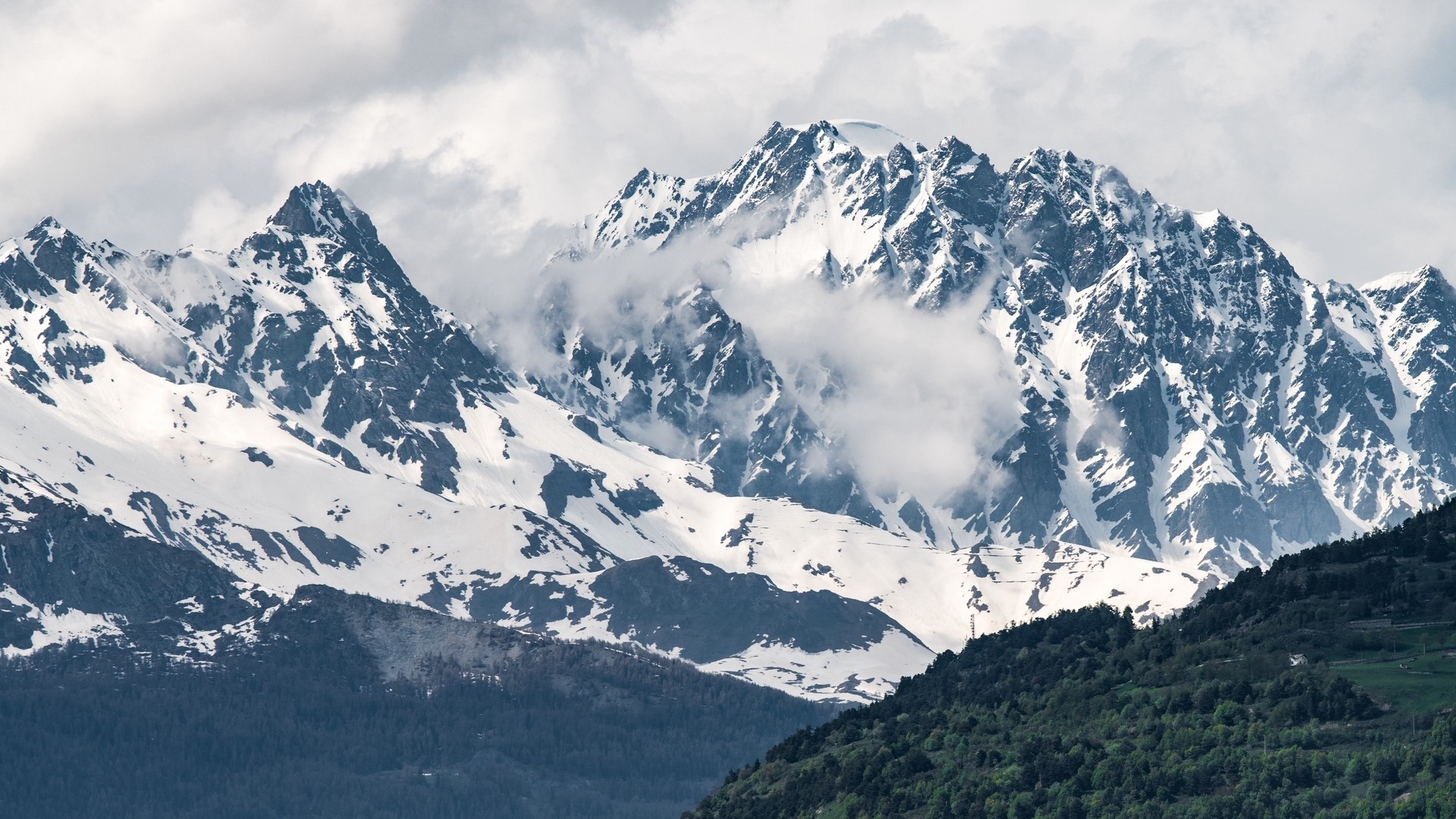 Snow-capped mountains with clouds and green foothills HD Wallpaper