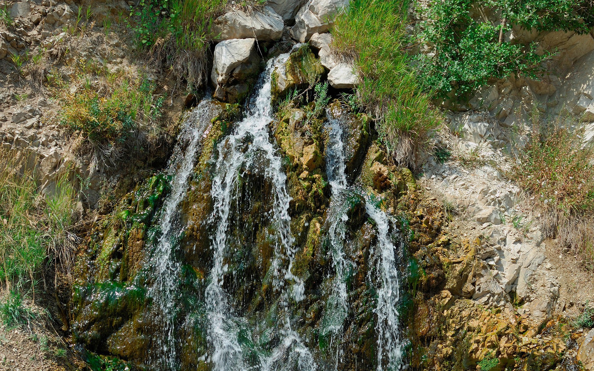 Waterfall cascading over mossy rocks HD Wallpaper