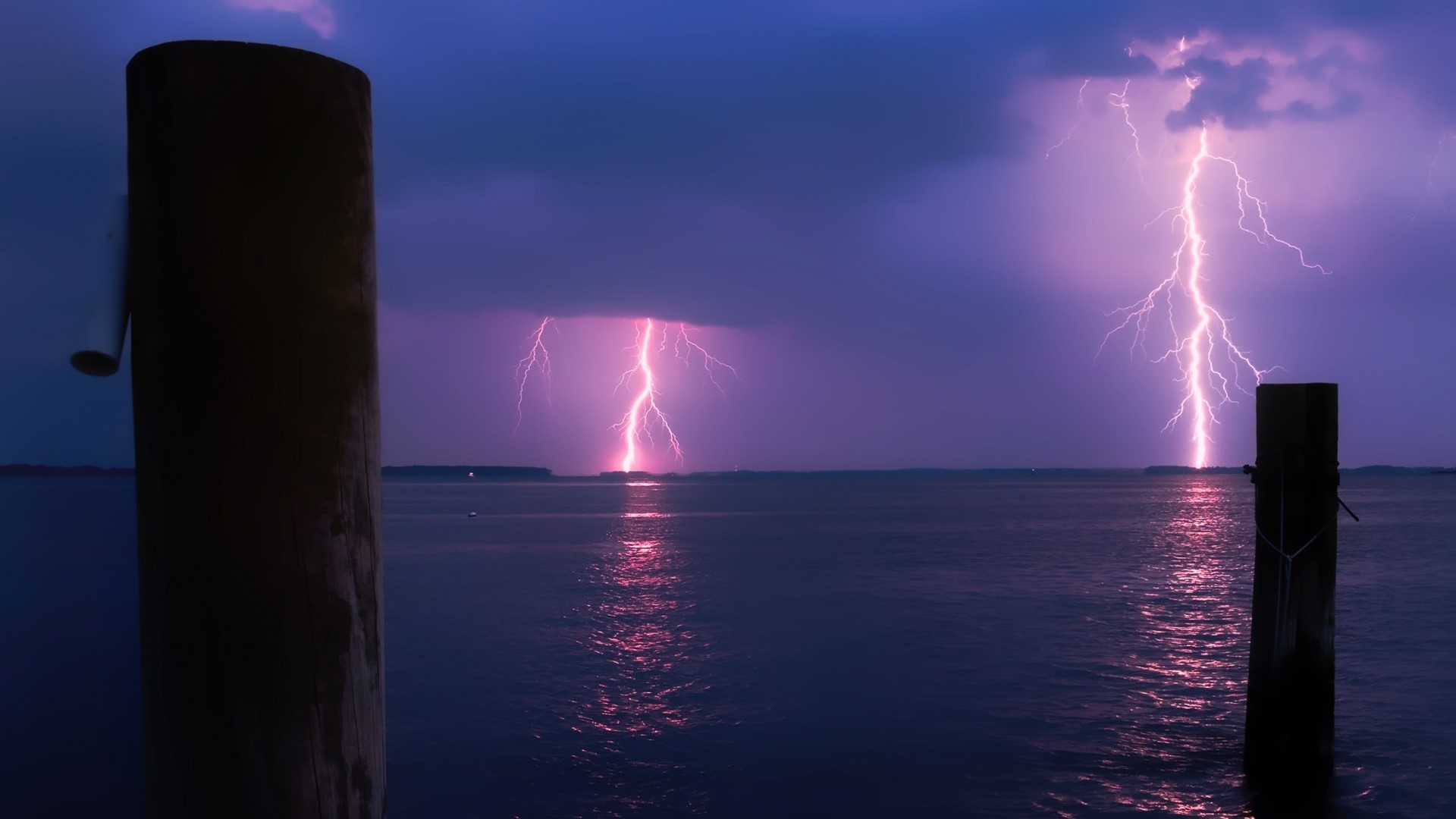 Lightning strikes over a body of water at night HD Wallpaper