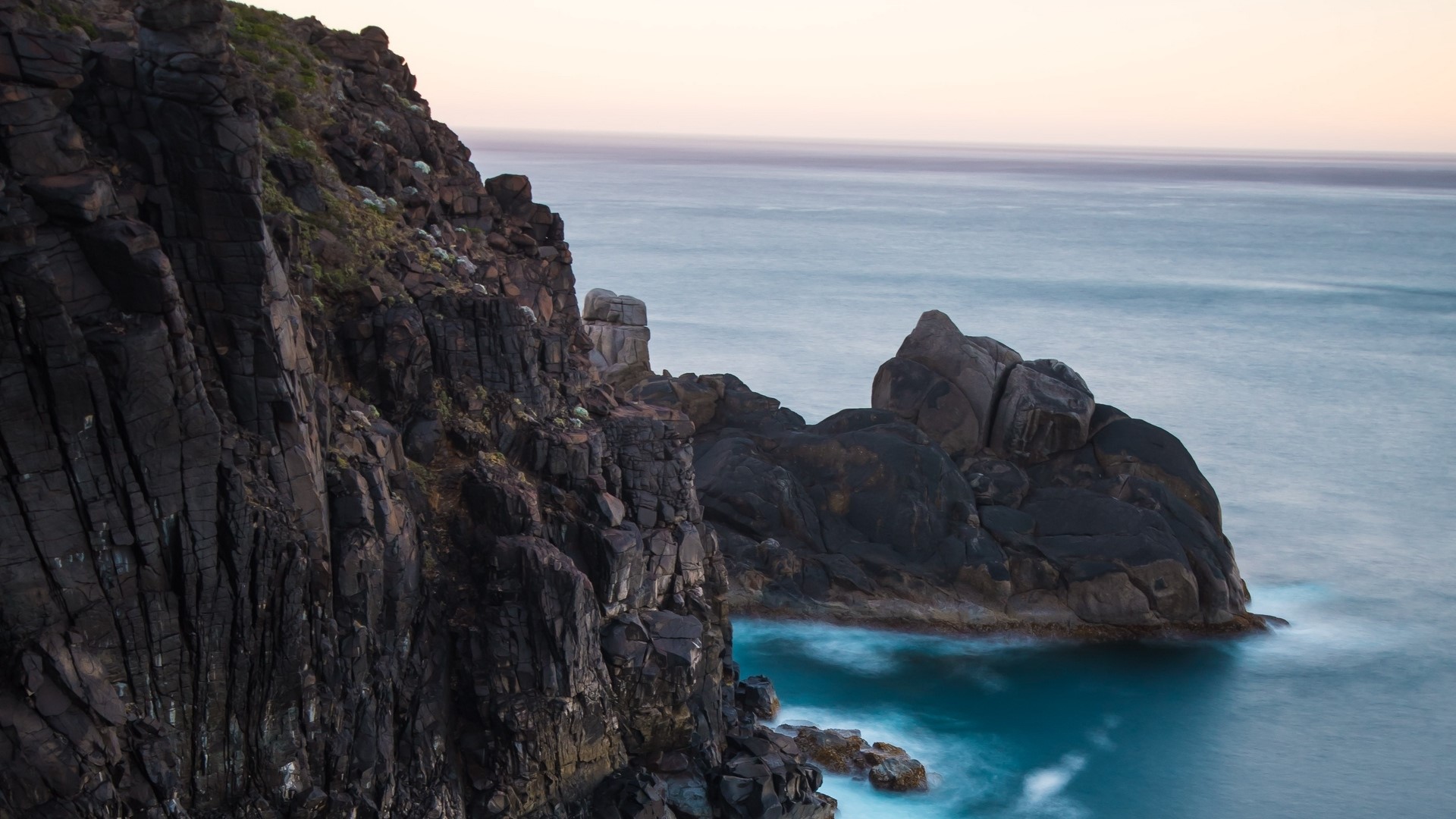Dark rocky cliffs overlooking the ocean at sunset HD Wallpaper