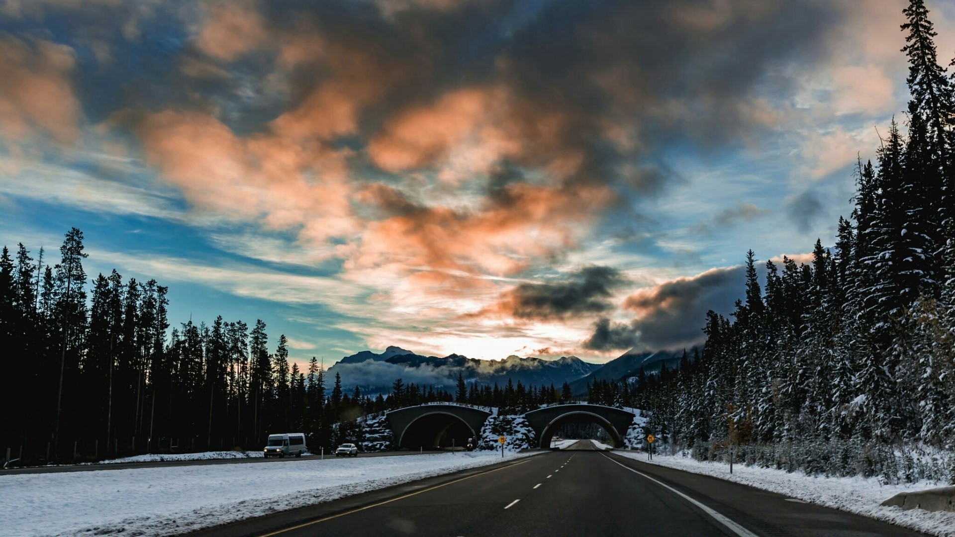Winter highway with snow-covered trees and mountains HD Wallpaper