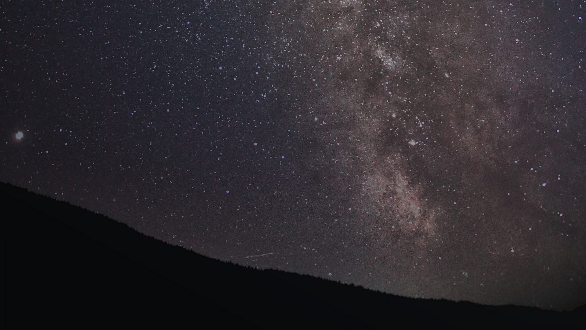 Milky Way galaxy over a dark mountain silhouette HD Wallpaper
