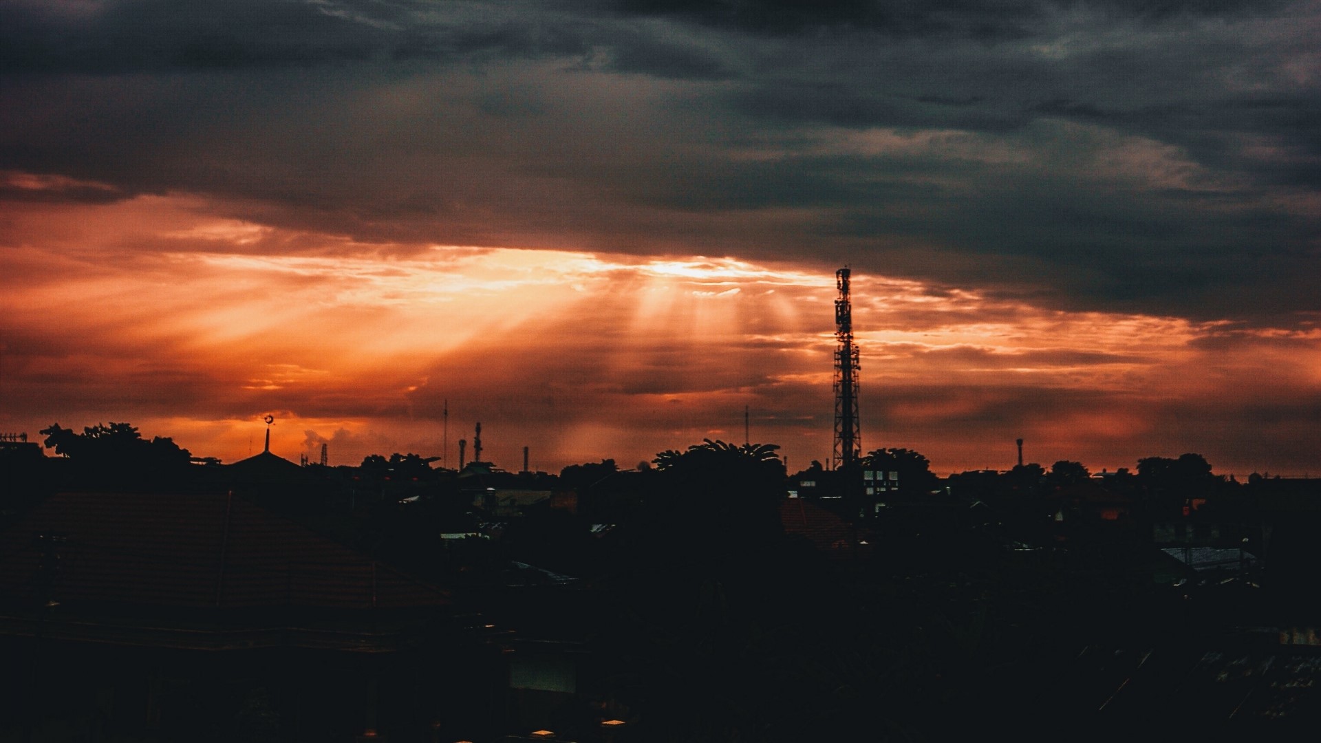 Sunset over a city with a cell tower HD Wallpaper