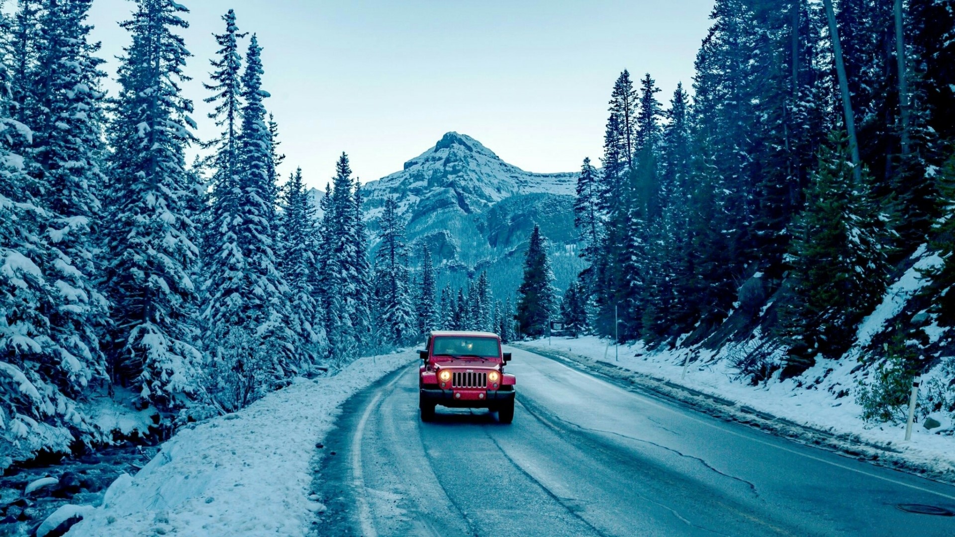 Red Jeep driving on a snowy mountain road HD Wallpaper