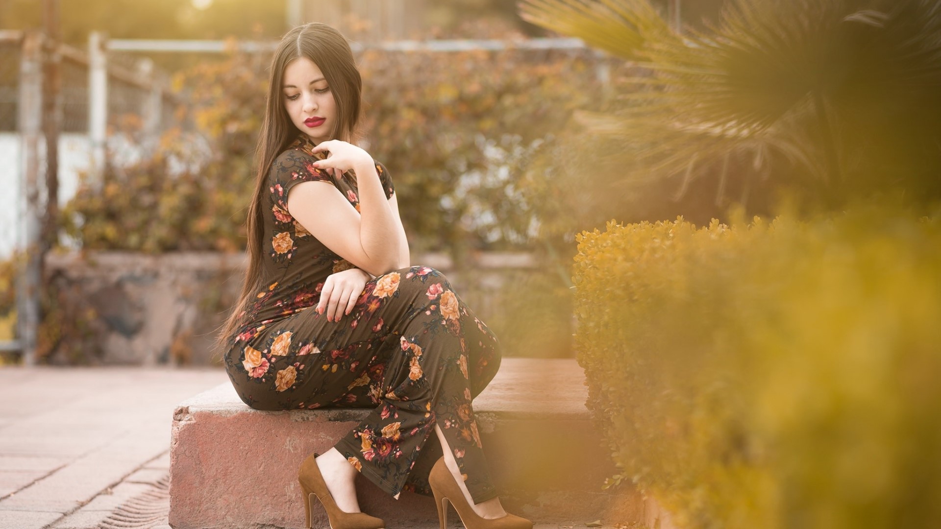 Woman in floral dress sitting outdoors HD Wallpaper
