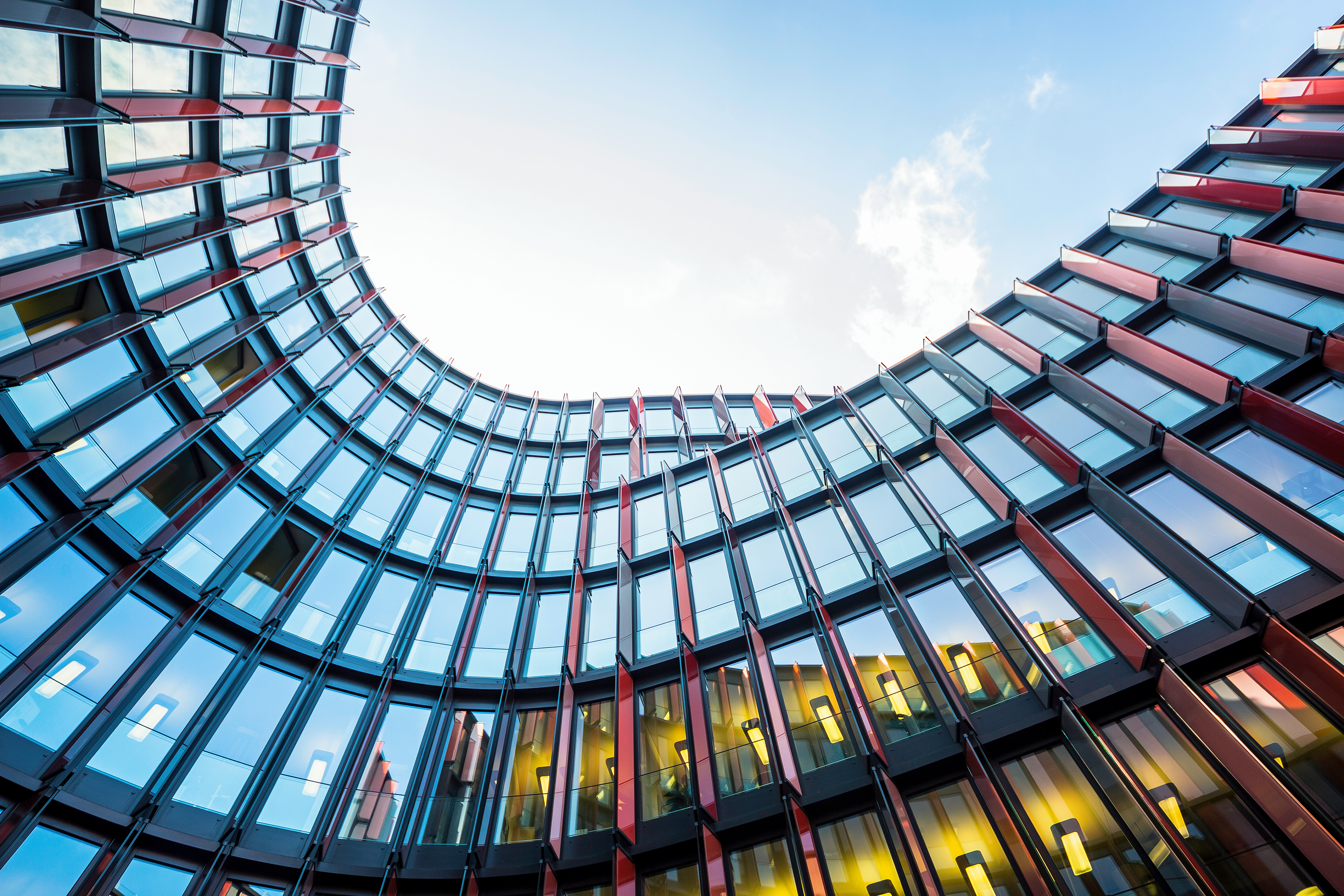 Curved glass building facade against a blue sky HD Wallpaper