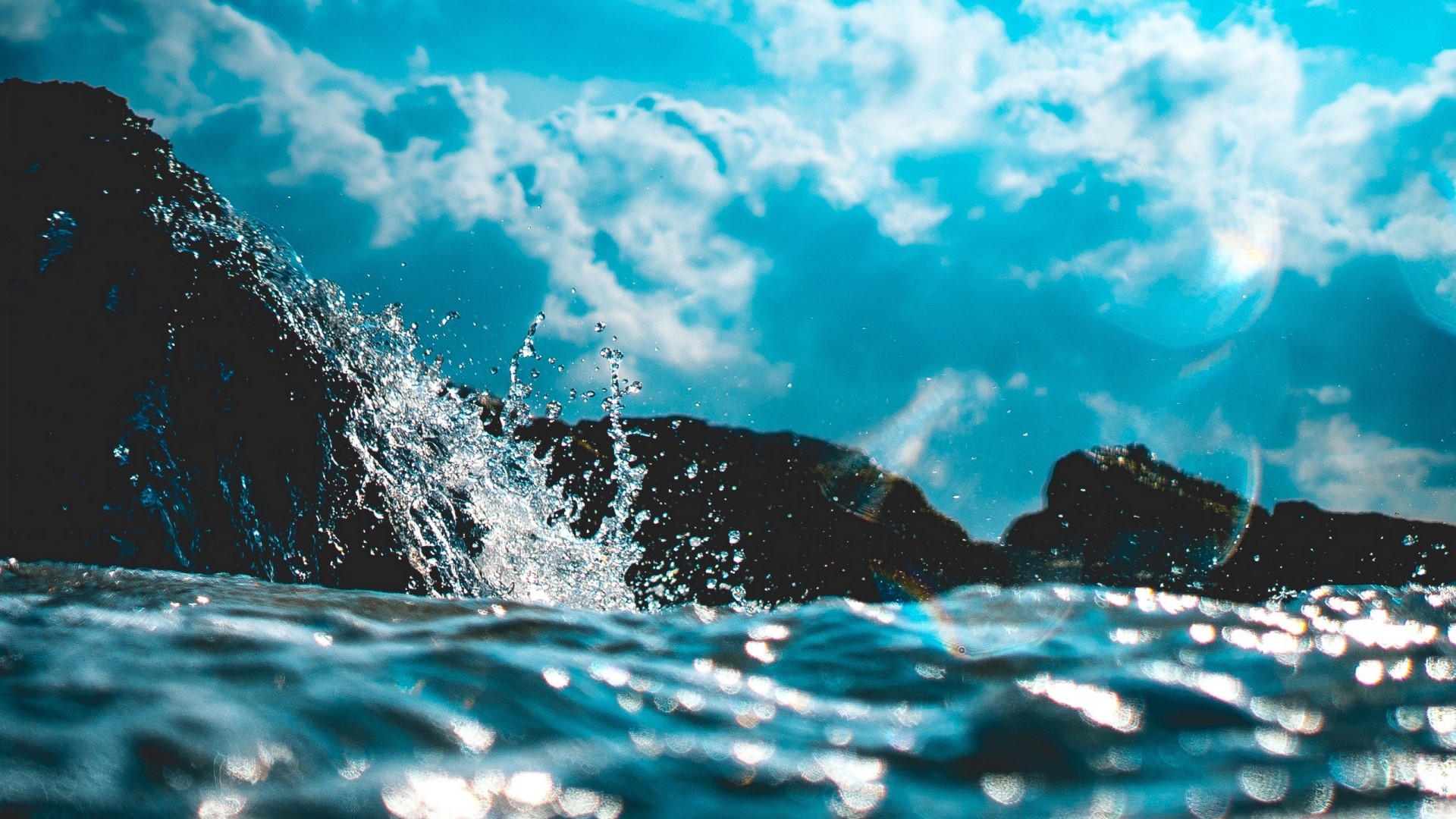 Waves crashing on rocks under a cloudy sky HD Wallpaper
