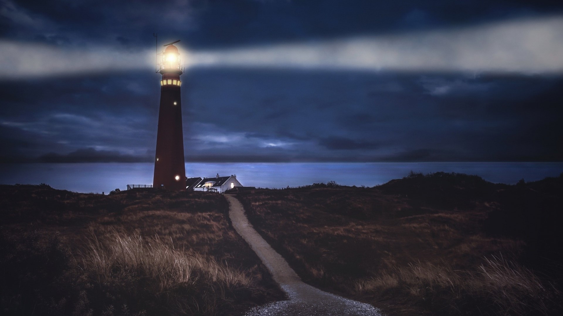 Lighthouse on a shore at night HD Wallpaper