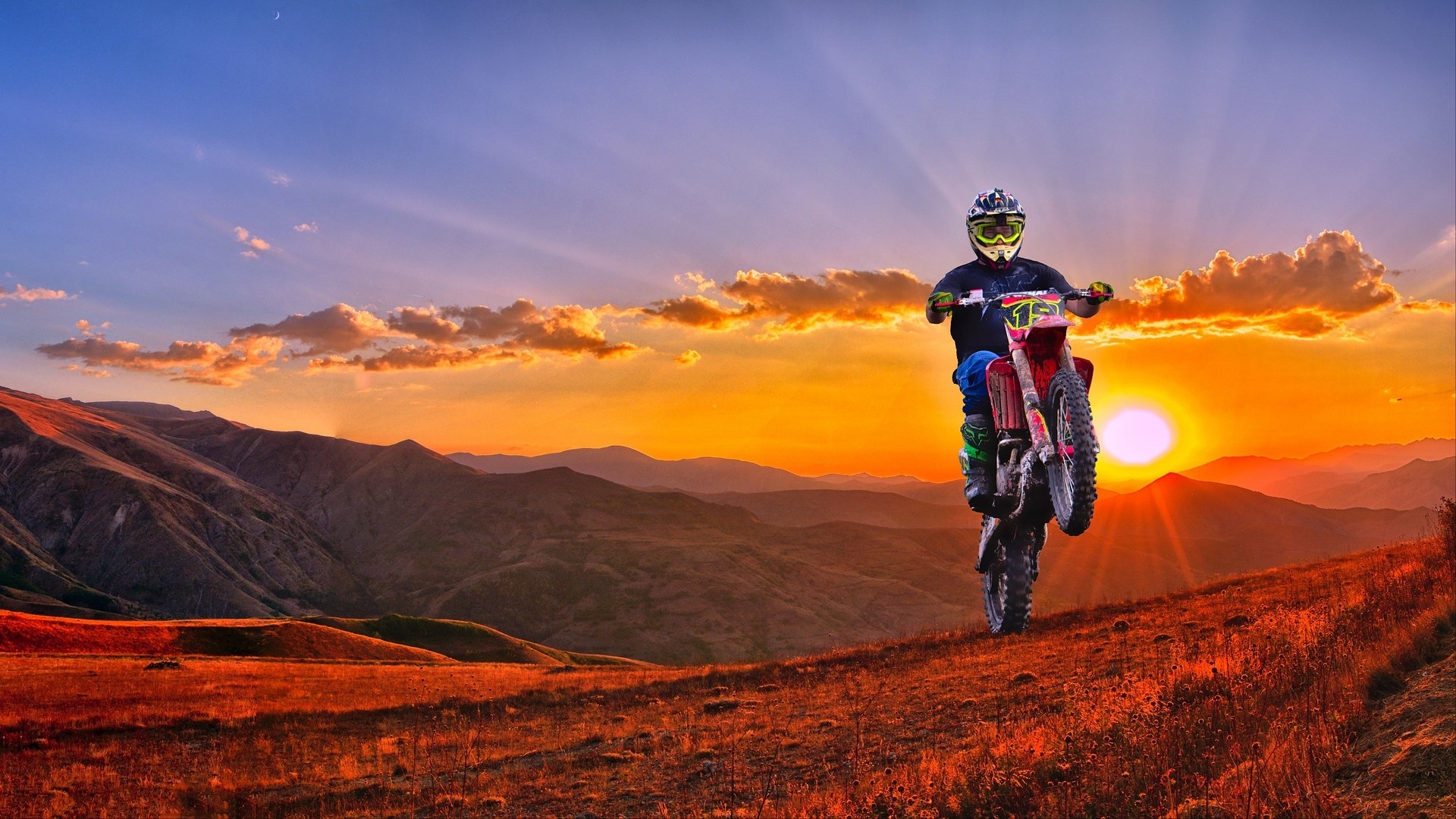 Motorcyclist performing a stunt at sunset HD Wallpaper