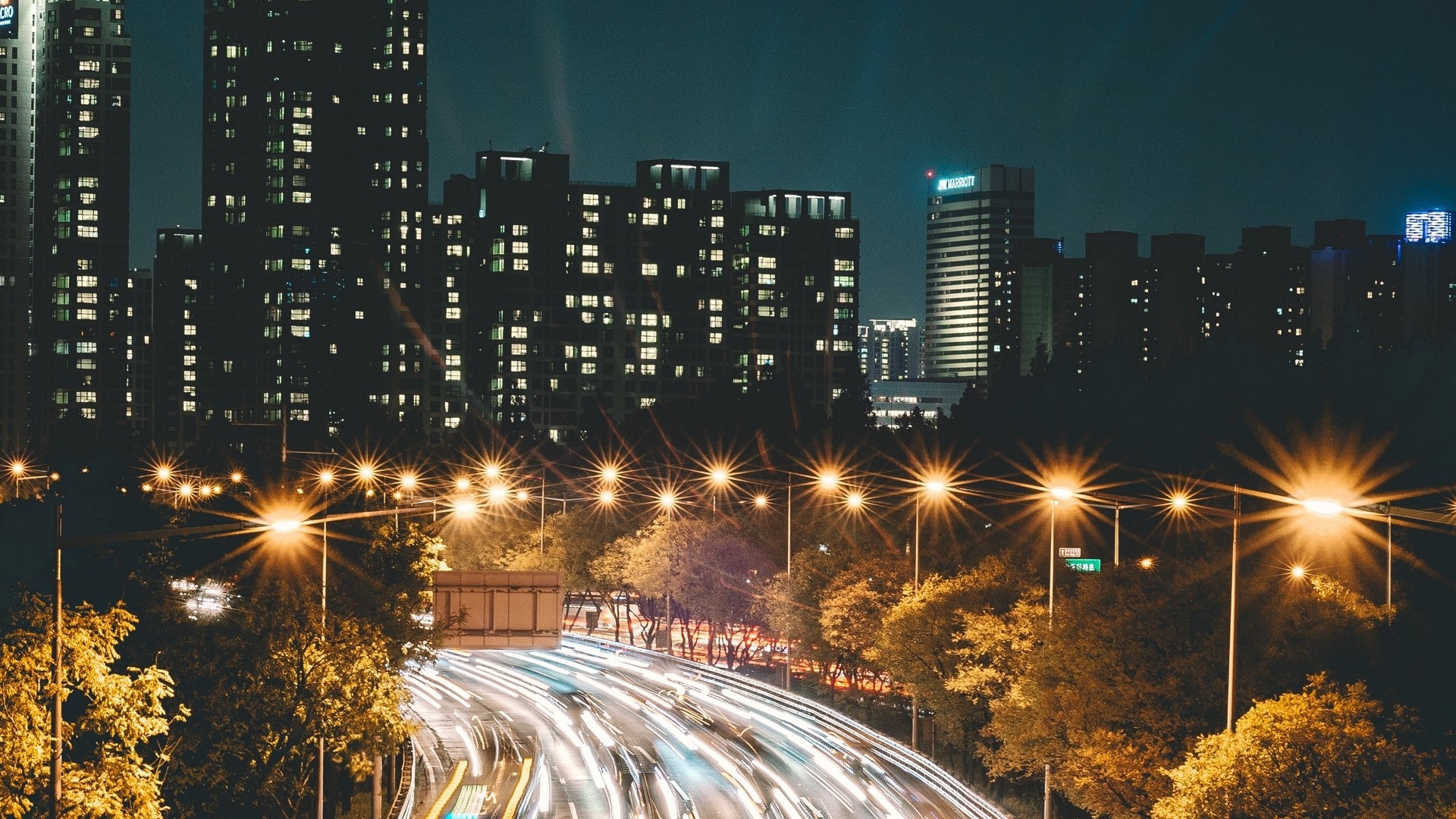 Night city highway with light trails and buildings HD Wallpaper