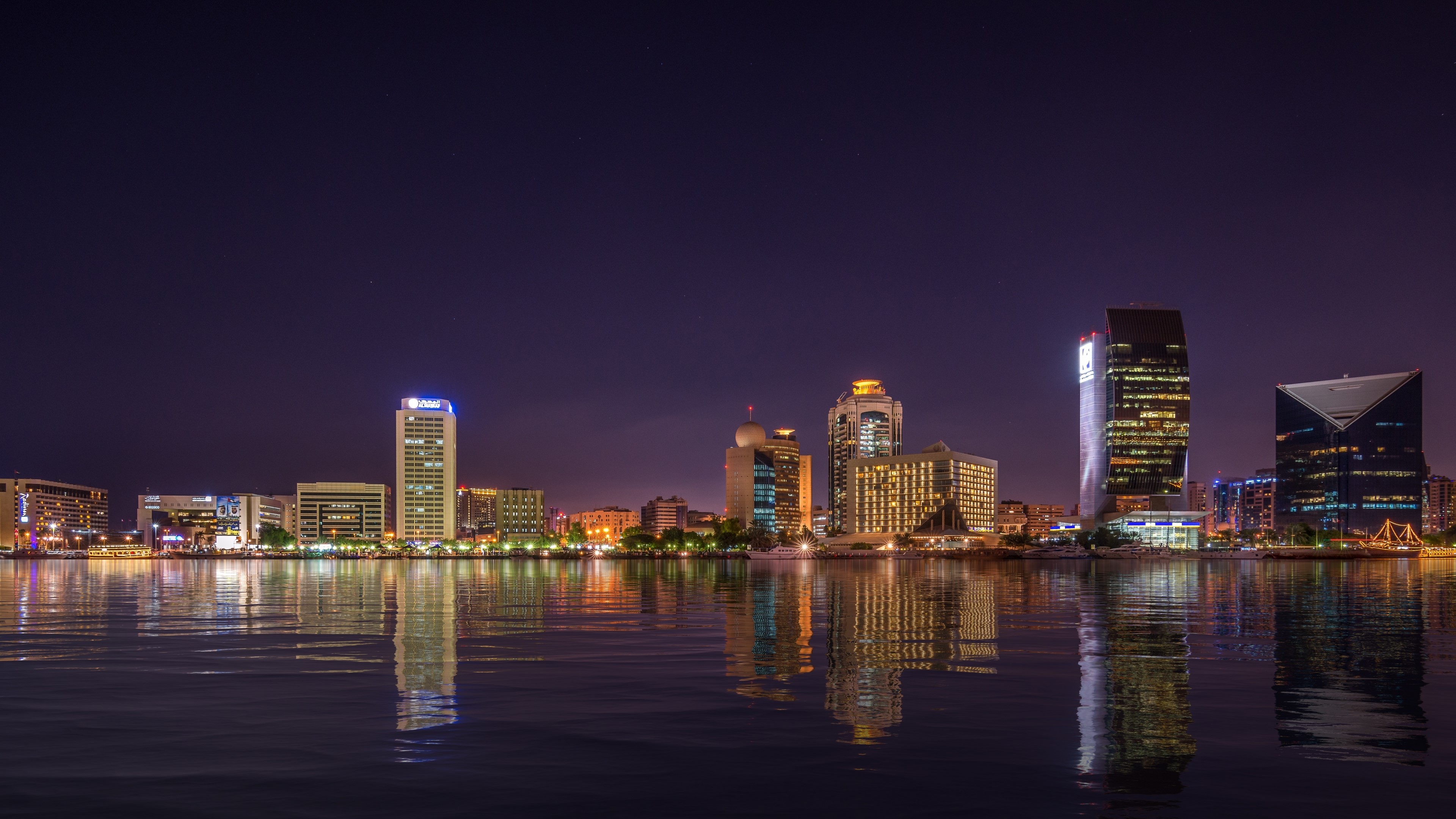 City skyline reflected in water at night HD Wallpaper