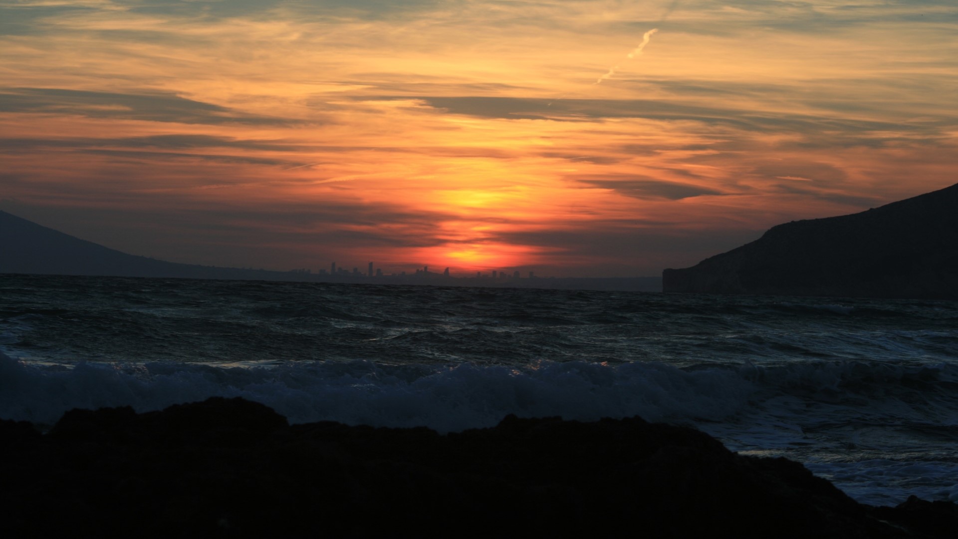 Sunset over the ocean with city skyline HD Wallpaper