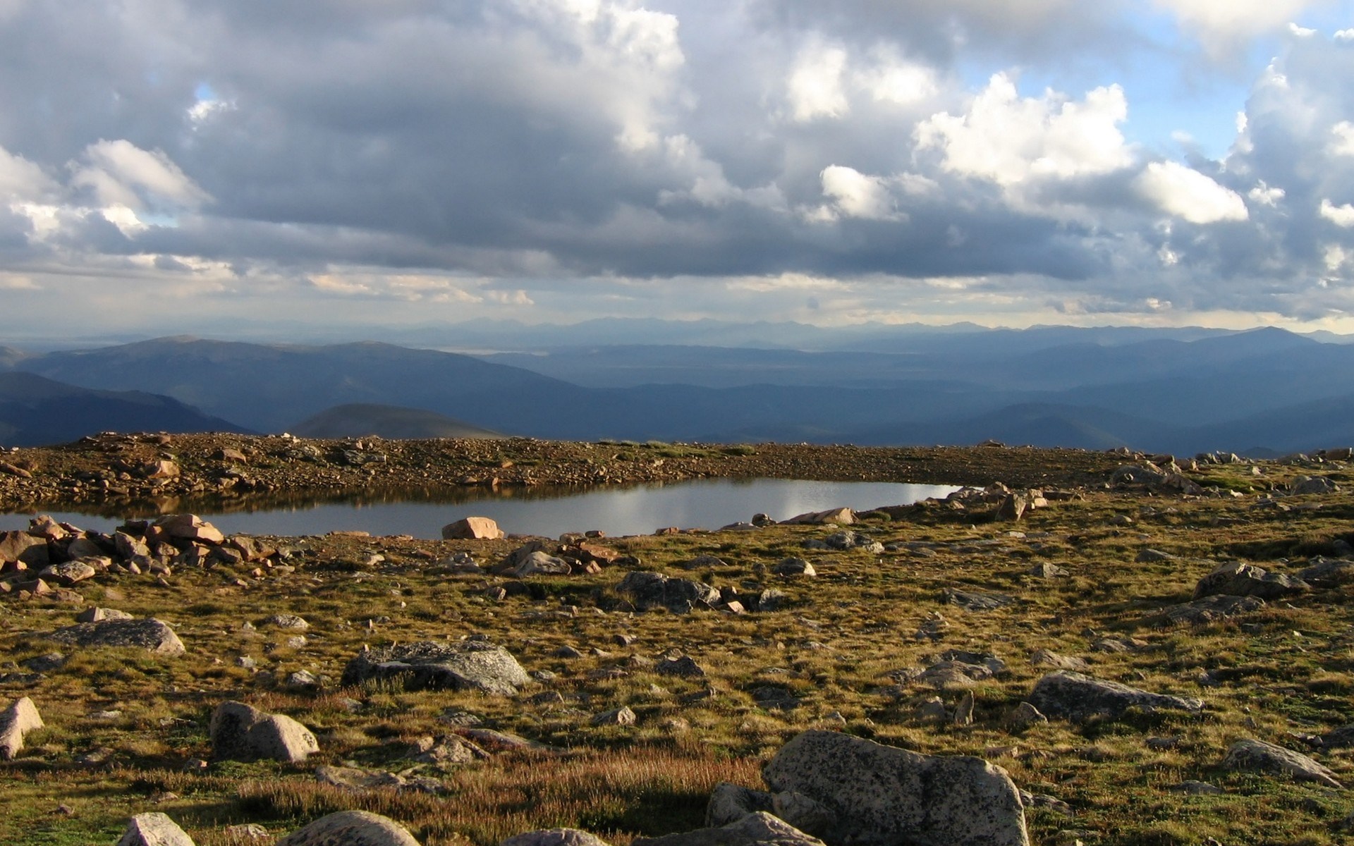 Mountain landscape with a small lake and cloudy sky HD Wallpaper