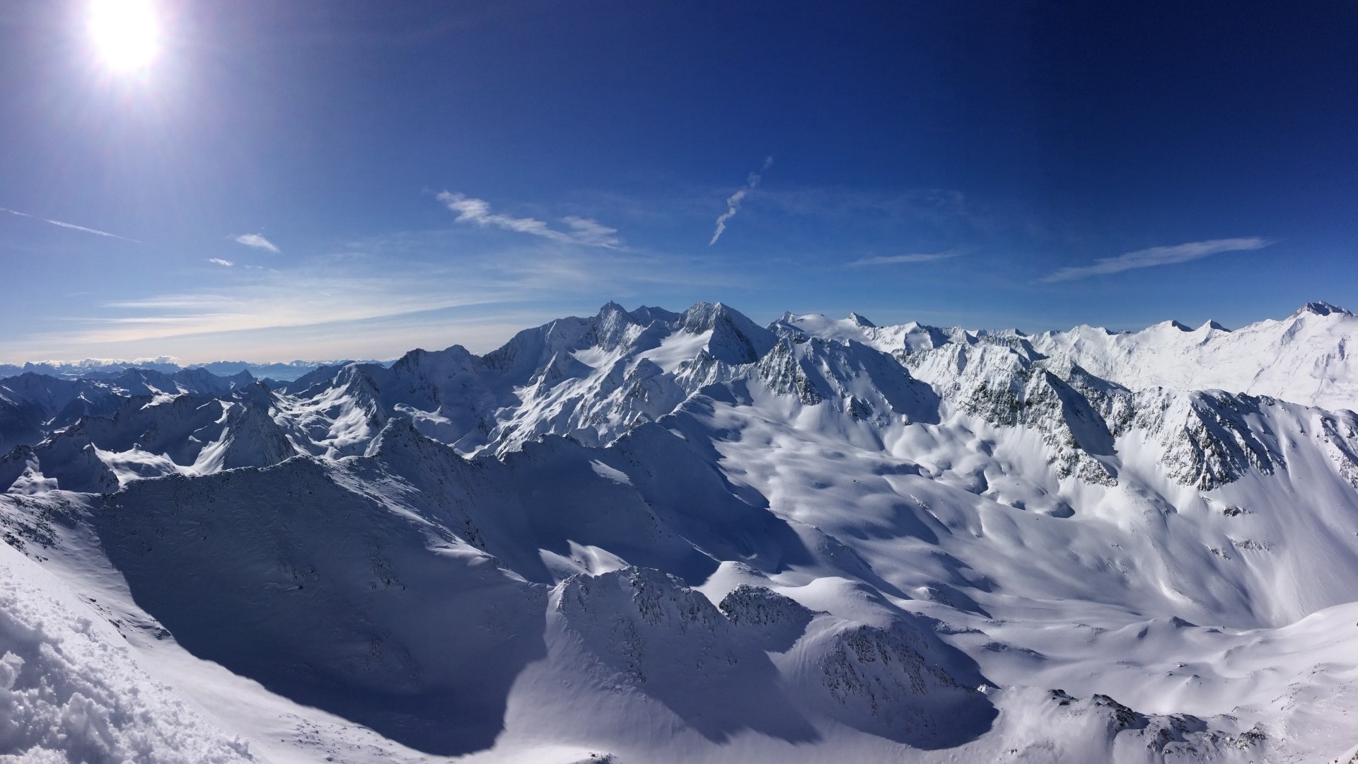 Snow-covered mountains under a bright sun HD Wallpaper