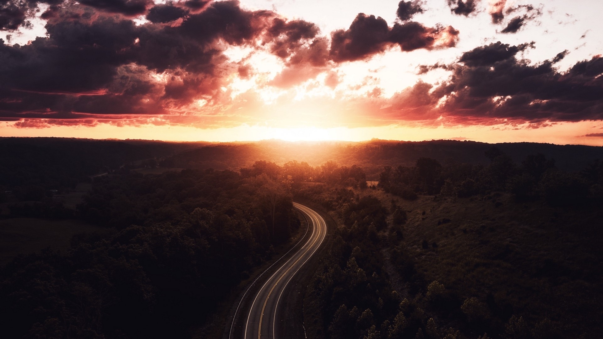 Road to sunset over rolling hills HD Wallpaper