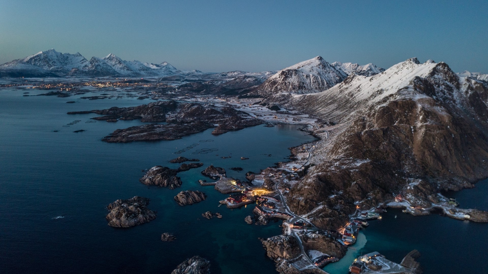 Aerial view of a Norwegian coastal village with snow-capped mountains HD Wallpaper
