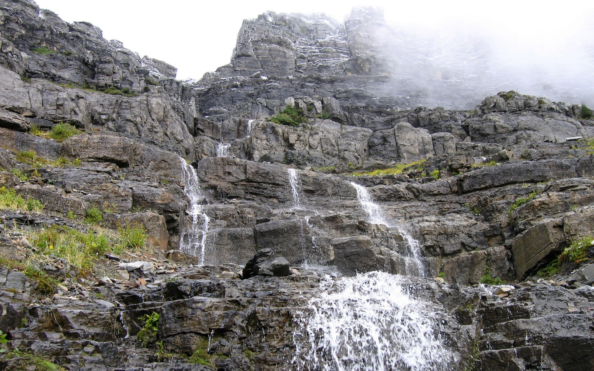 Waterfall cascading down a rocky mountain slope HD Wallpaper
