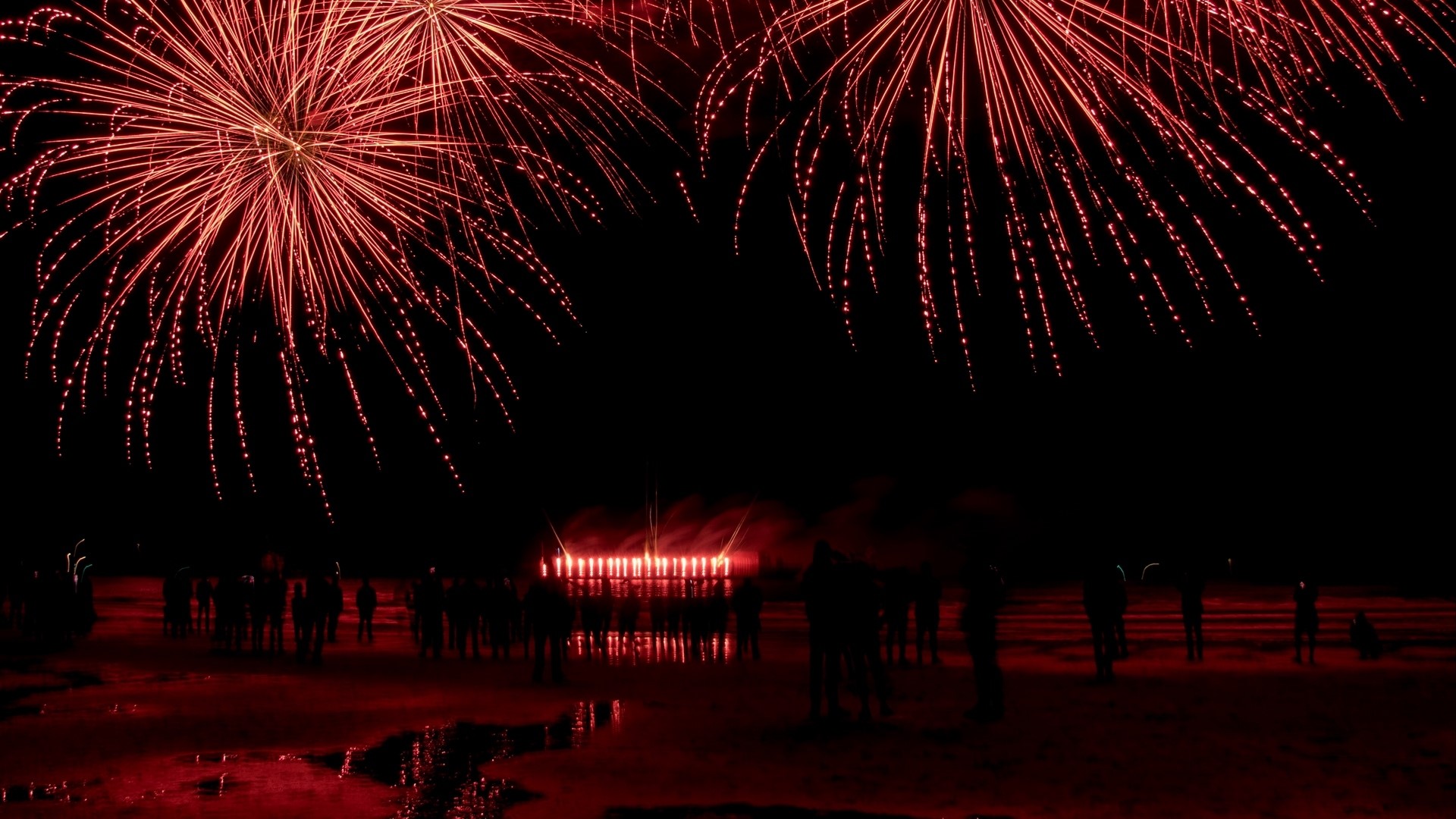 Red Fireworks Display Over a Beach Crowd HD Wallpaper