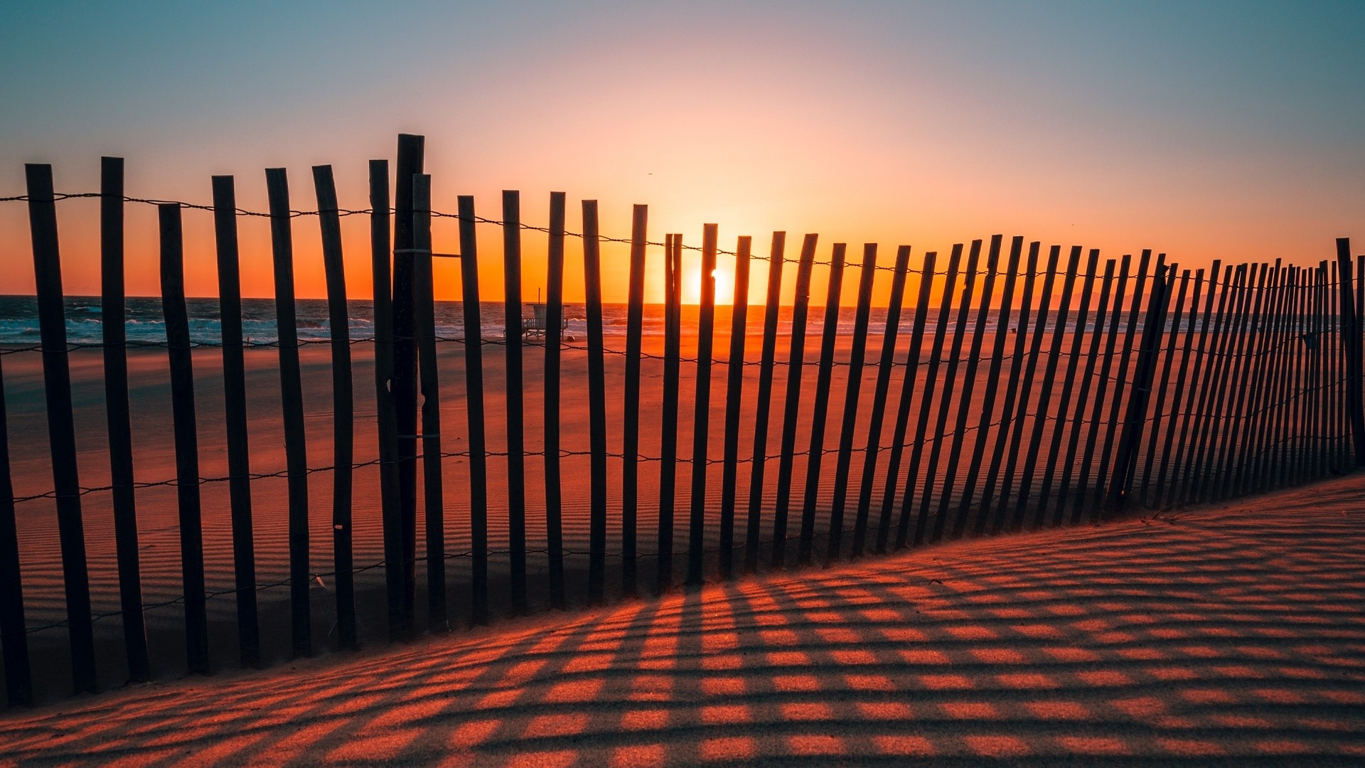 Sunset over the ocean behind a wooden fence HD Wallpaper