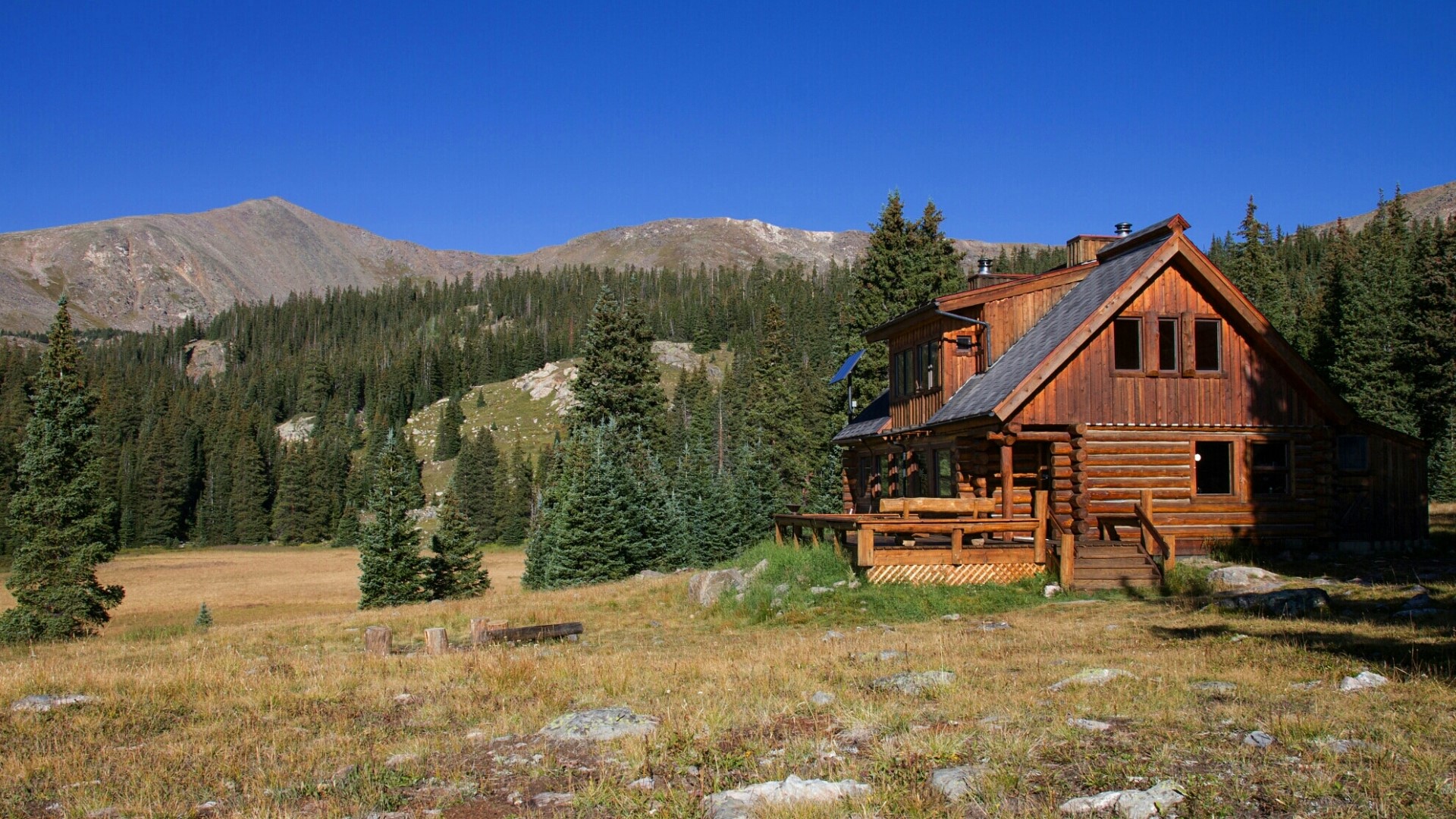 Log cabin in a mountain forest clearing HD Wallpaper